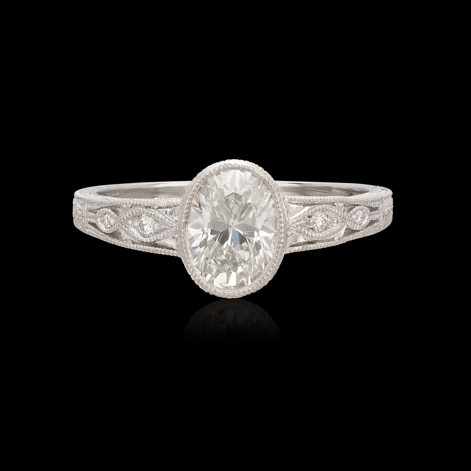 Gorgeous custom Platinum ring features a 0.99 carat oval diamond bezel set in a delicate design featuring expert milgrain, filigree and hand engraving. The center stone has been graded as I color and SI clarity, delivering plenty sparkle and fire.