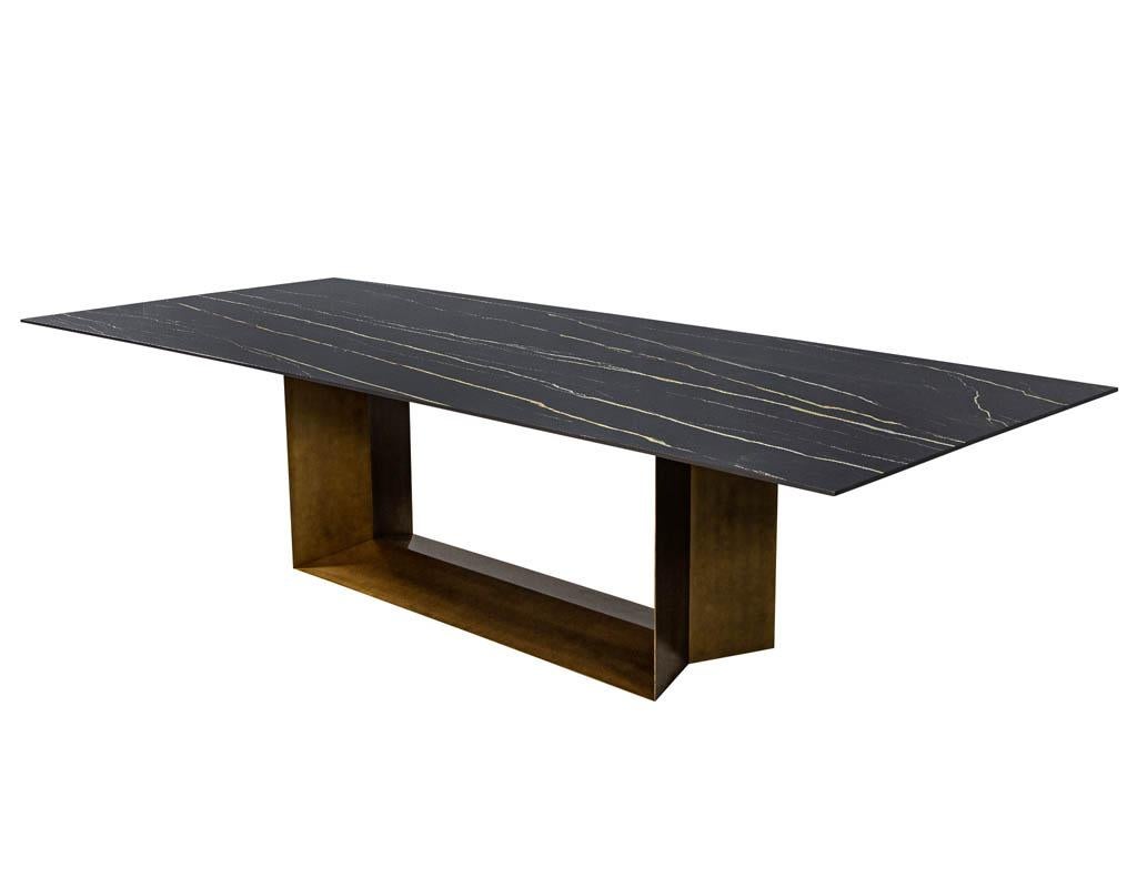 Custom porcelain modern dining table with brass finished base by Carrocel. Featuring a black lacquered tapered wood edge and geometric antique brass finished base. Please note this table is made to order, porcelain top may vary slightly in pattern.