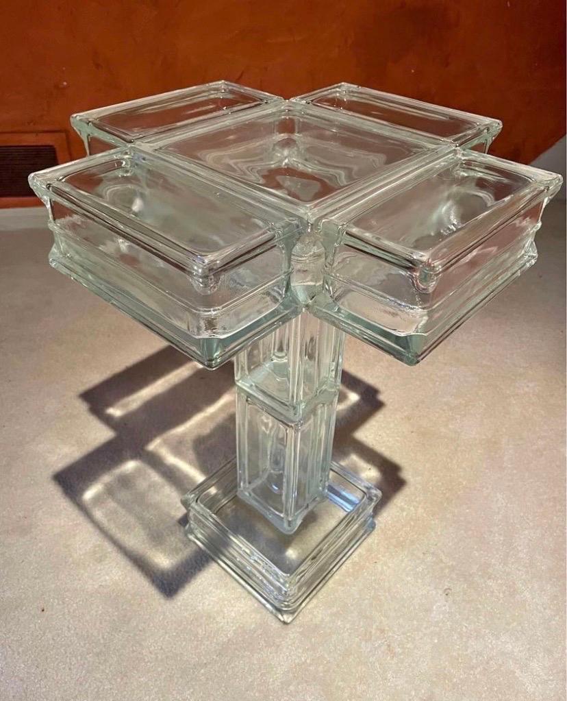 This is a custom-made glass block table dating to the 1990s. The blocks have a bit of a blue hue to them. The translucent adhesive has not yellowed from age and looks fresh.

It can serve as an unobtrusive pedestal to display a sculpture upon, and
