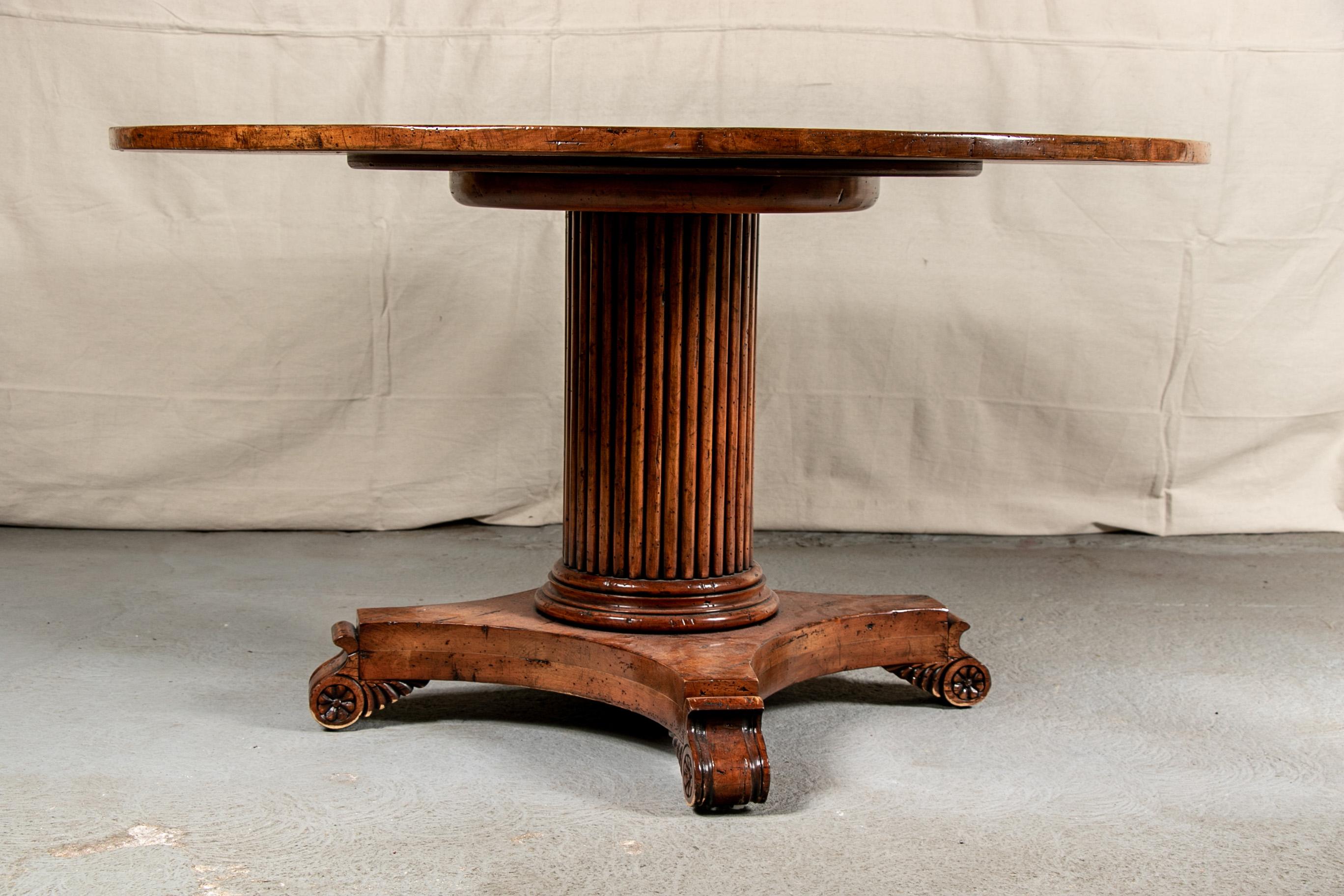 Custom Provincial circular dining table, possibly Grange or Guy Chaddock, pine table with banded plank top in a glazed finish, ribbed column support with for curved legs and carved scrolled feet with rosette ends. 

Condition: Expected signs of