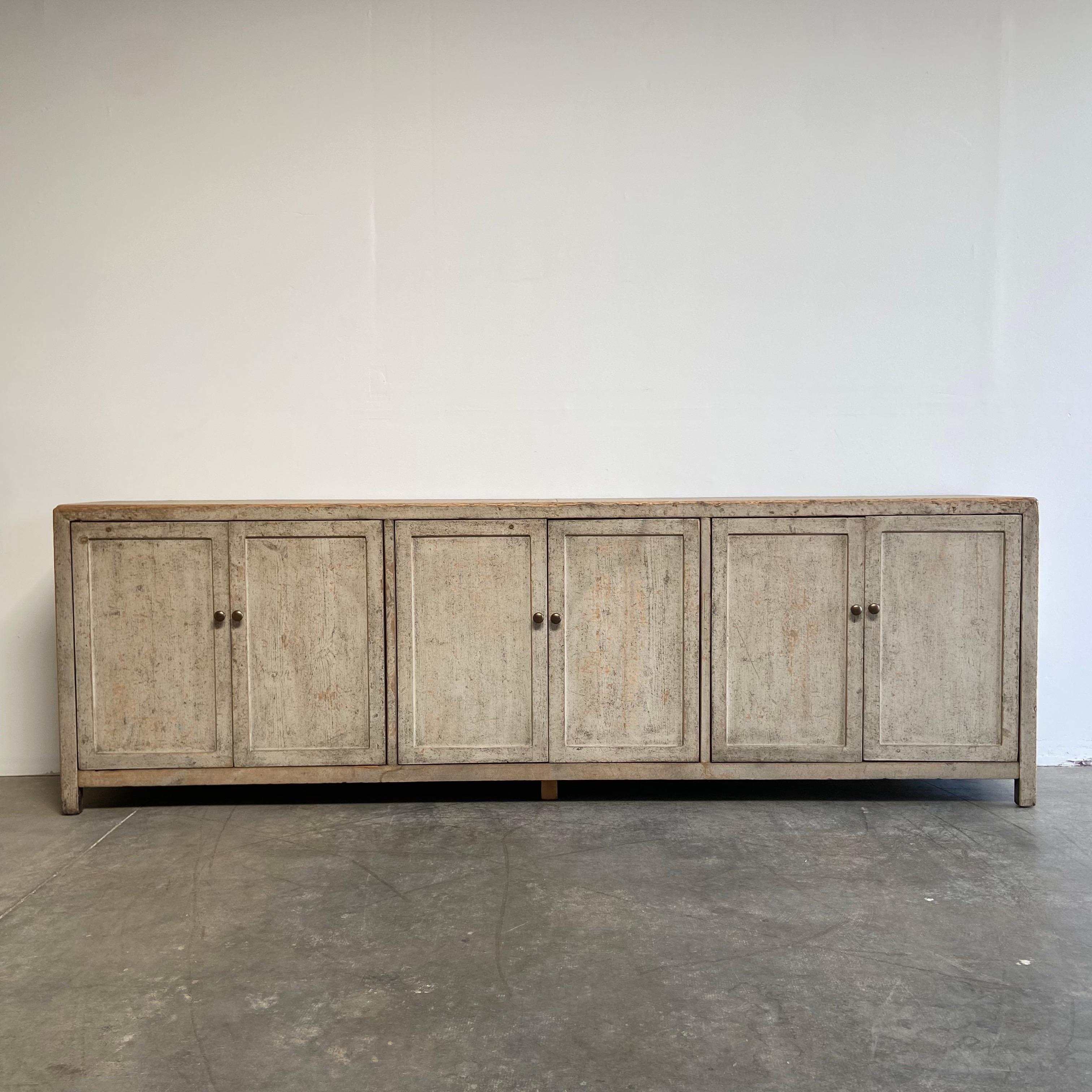 Custom Reclaimed wood sideboard
Size: 112-1/2” W x 18” D x 36” H
A distressed rustic painted finish in a natural linen color with subtle wood and greyish tones running through.
Plenty of storage, with doors, and a shelf behind each set of