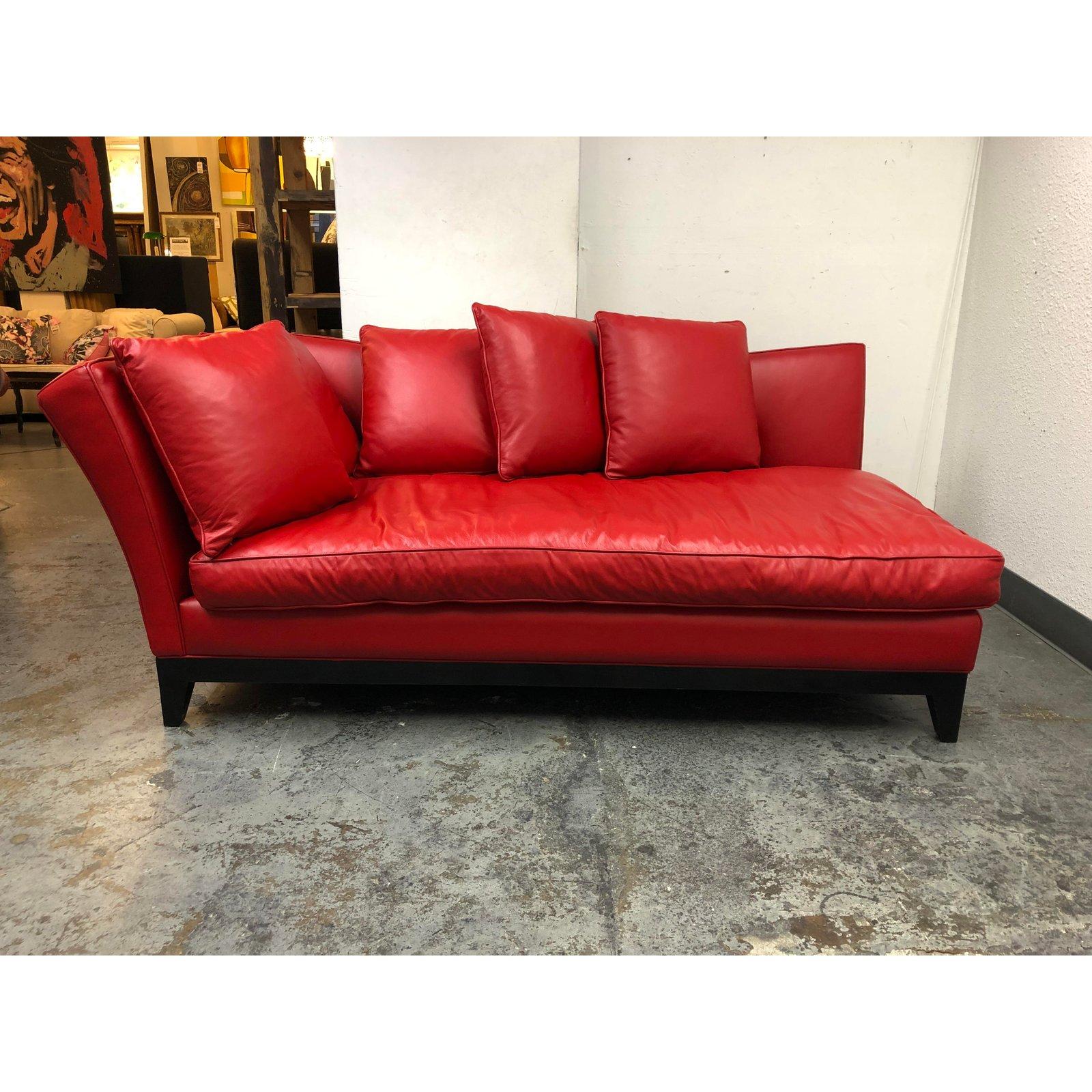 A custom lounge chaise sofa. A sleek and luxurious design. Upholstered in a deep cherry red leather. The base is wood with tapered legs in a black finish. Accompanied with five square back cushions and a single seat cushion. The pillow inserts are