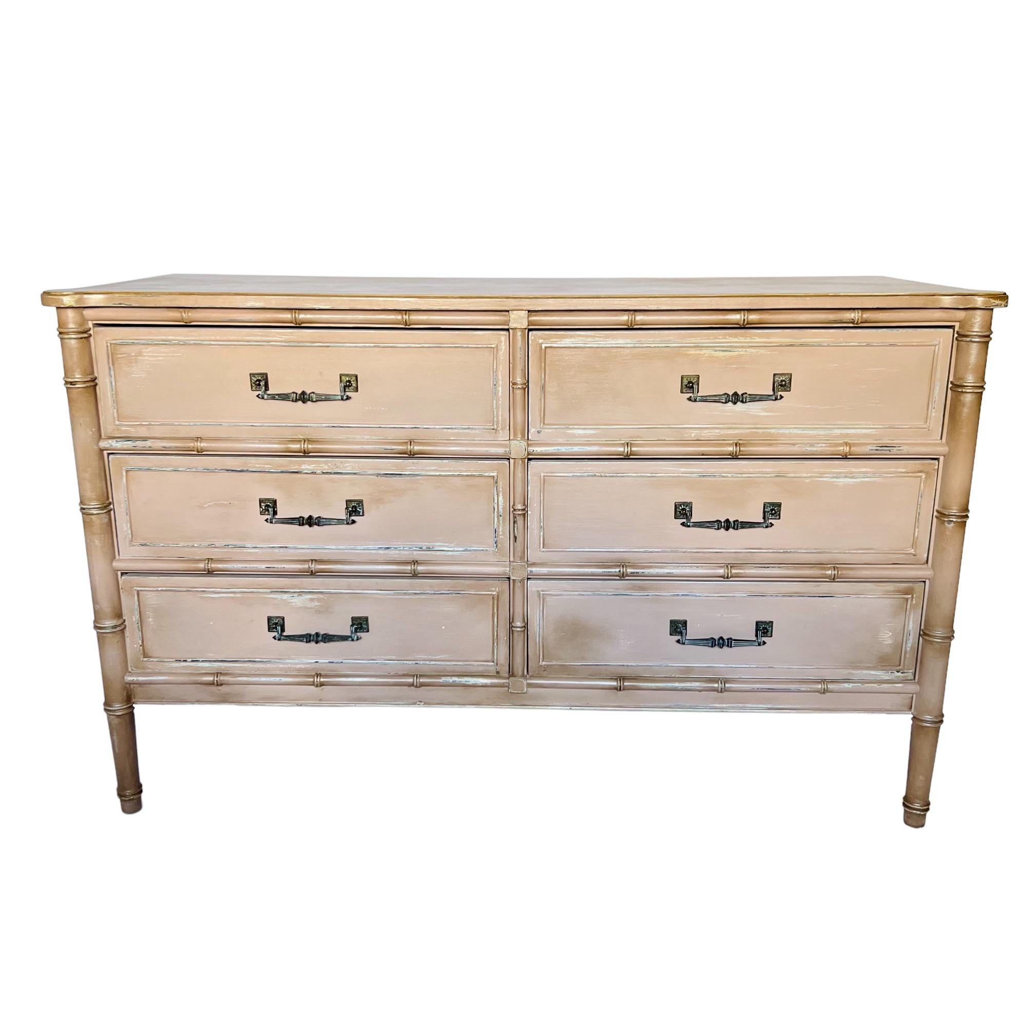 This vintage Henry Link Palm Beach Regency faux bamboo dresser has been custom refinished in a distressed satin light dusty pink with dark wax details and pearlescent and gold highlights. It features six drawers adorned with bronze handles and lined