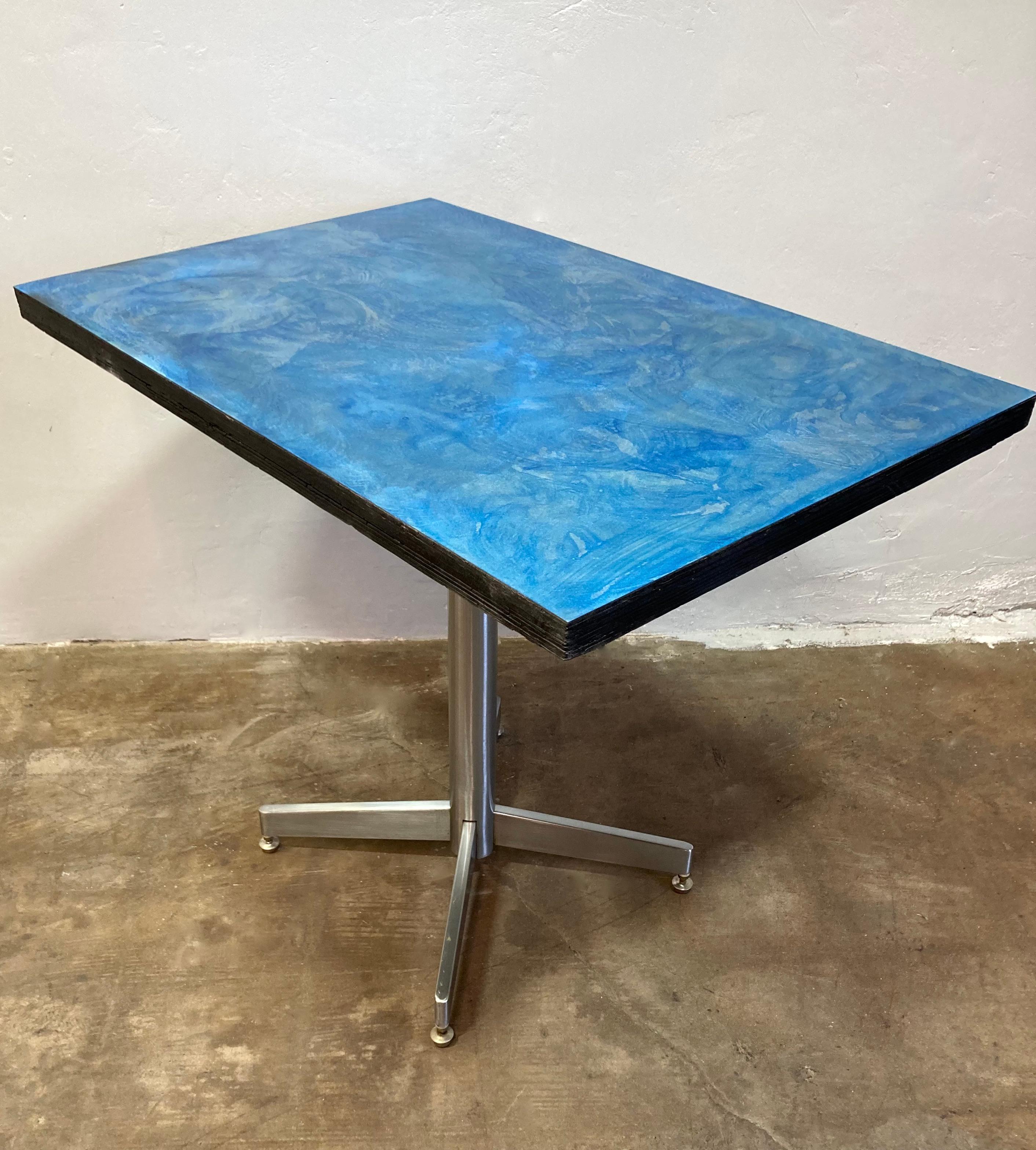 Rehab Vintage Interiors original mesa de bistro reformada. La base de acero cepillado se ha rematado con un tablero de madera recuperada y acero patinado azul personalizado. La mesa bistro de tamaño práctico encaja perfectamente en una cocina o