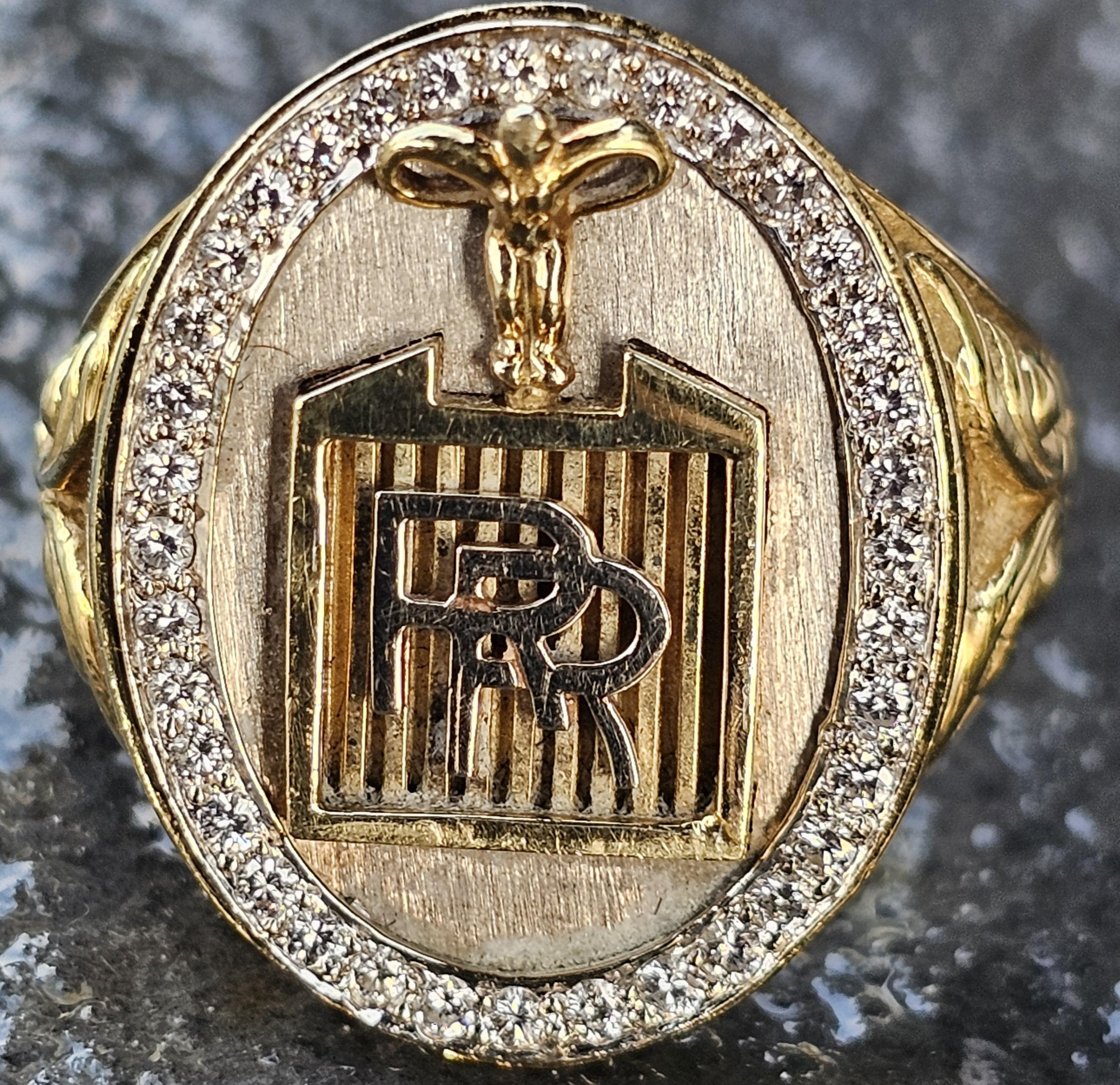 This exquisite ring is a remarkable piece for any jewelry Rolls Royce enthusiast. Crafted from a blend of 18k white gold, and yellow gold, it features a striking design with a central motif and a border of white diamonds. The ring is a size 12.5,