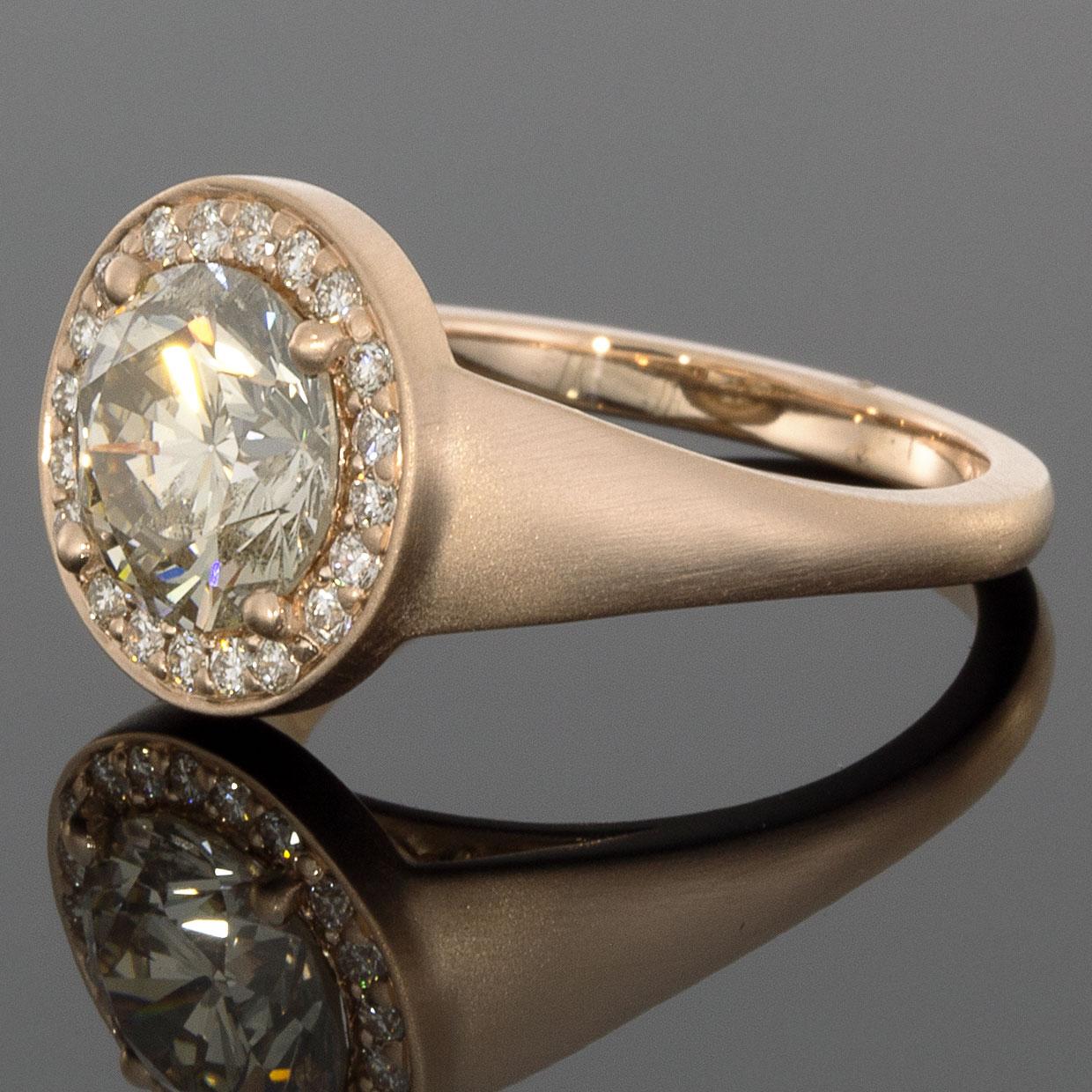 A one-of-a-kind design by our experts, this stunning ring is radiant wrapped in the warmth of luscious rose gold. The GIA certified center diamond is showcased by a halo of brilliant white diamonds, & the tapered shank flows gracefully down the