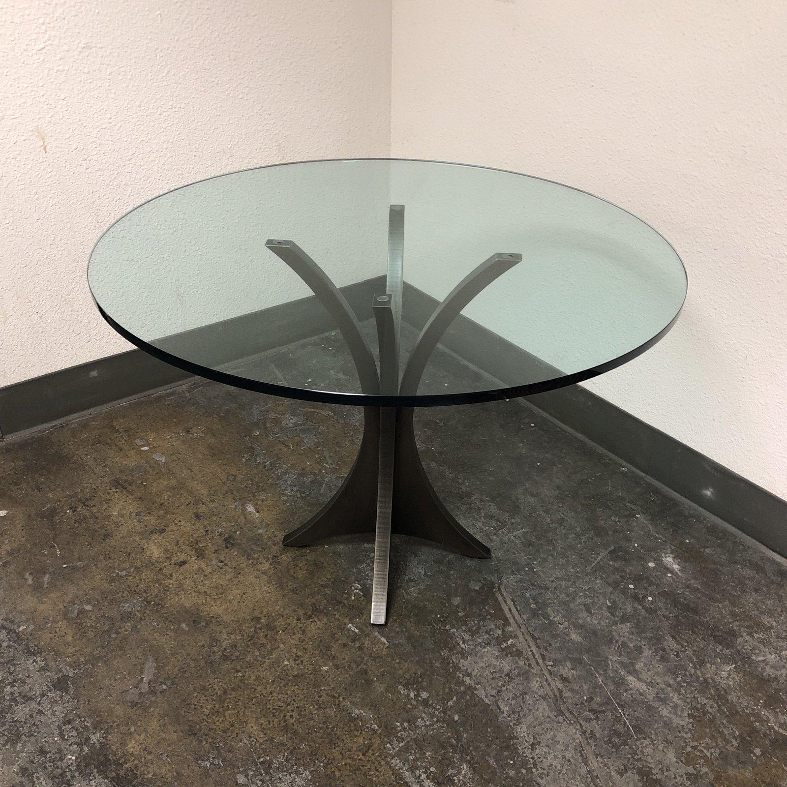 A custom round table. Settle down to a bowl of Modern-O's in your minimalist breakfast nook with this arched iron frame and thick glass kitchen table. A faint texture adds a natural feel to the solid pedestal iron bars.