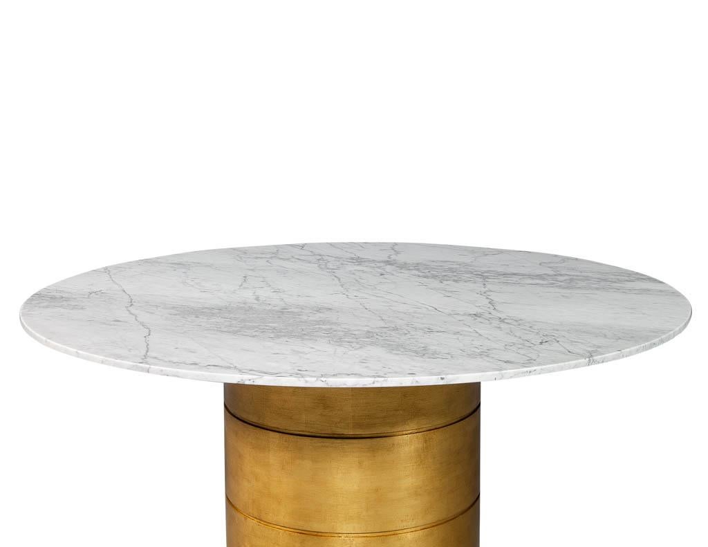 Custom round marble top dining table with gold leafed bezel base. Elegant and stunning, this stone top table is custom made by Carrocel. With a bezel style gold leaf base and adorned with a select Bianca Carrara stone top this table will be a show