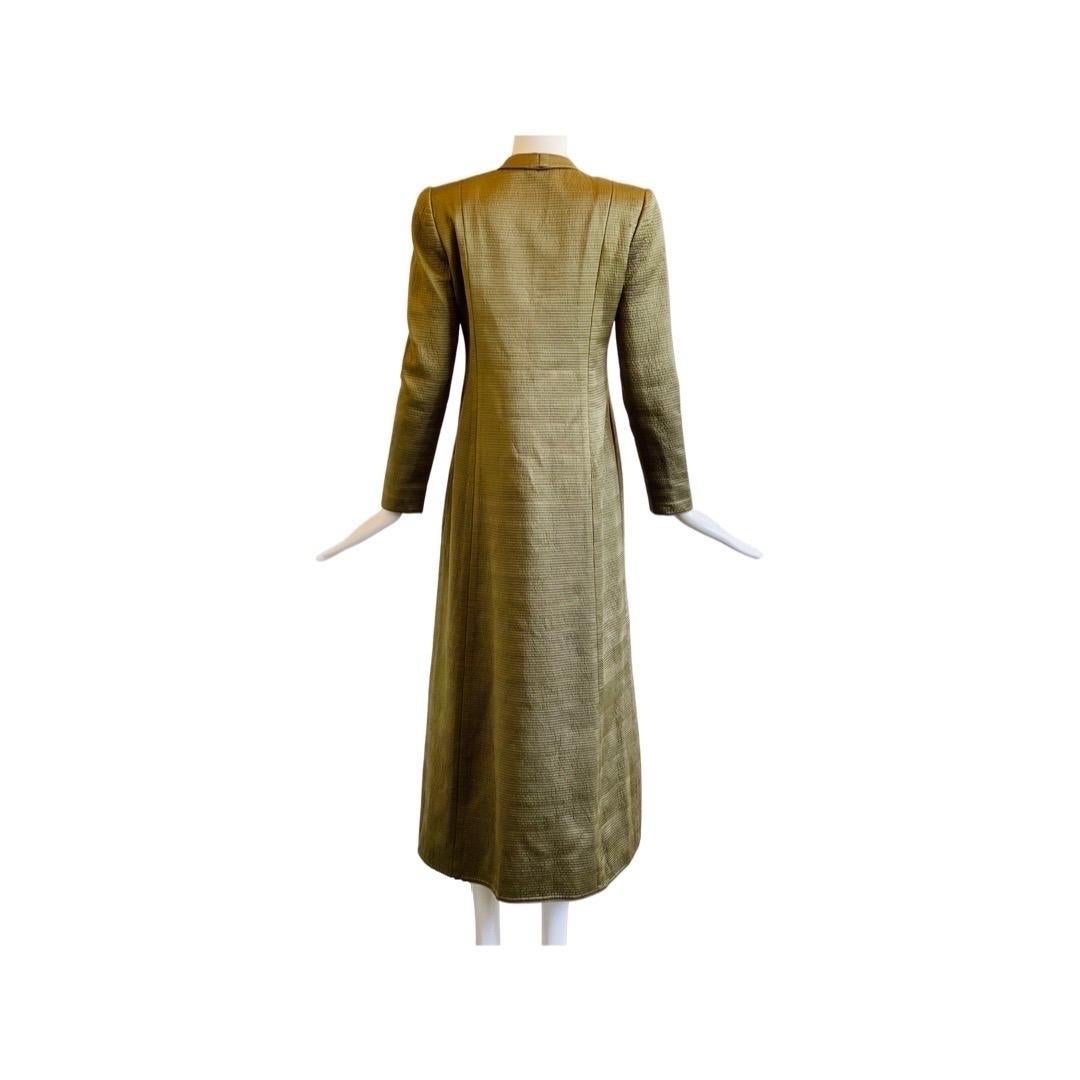 Beautifully made opera maxi coat in a olive green satin, done in a lined quilted technique.  There is a mandarin collar and a line of cloth shank buttons and loop closures and is fitted in to the waist before flaring out.  Two external pockets sit