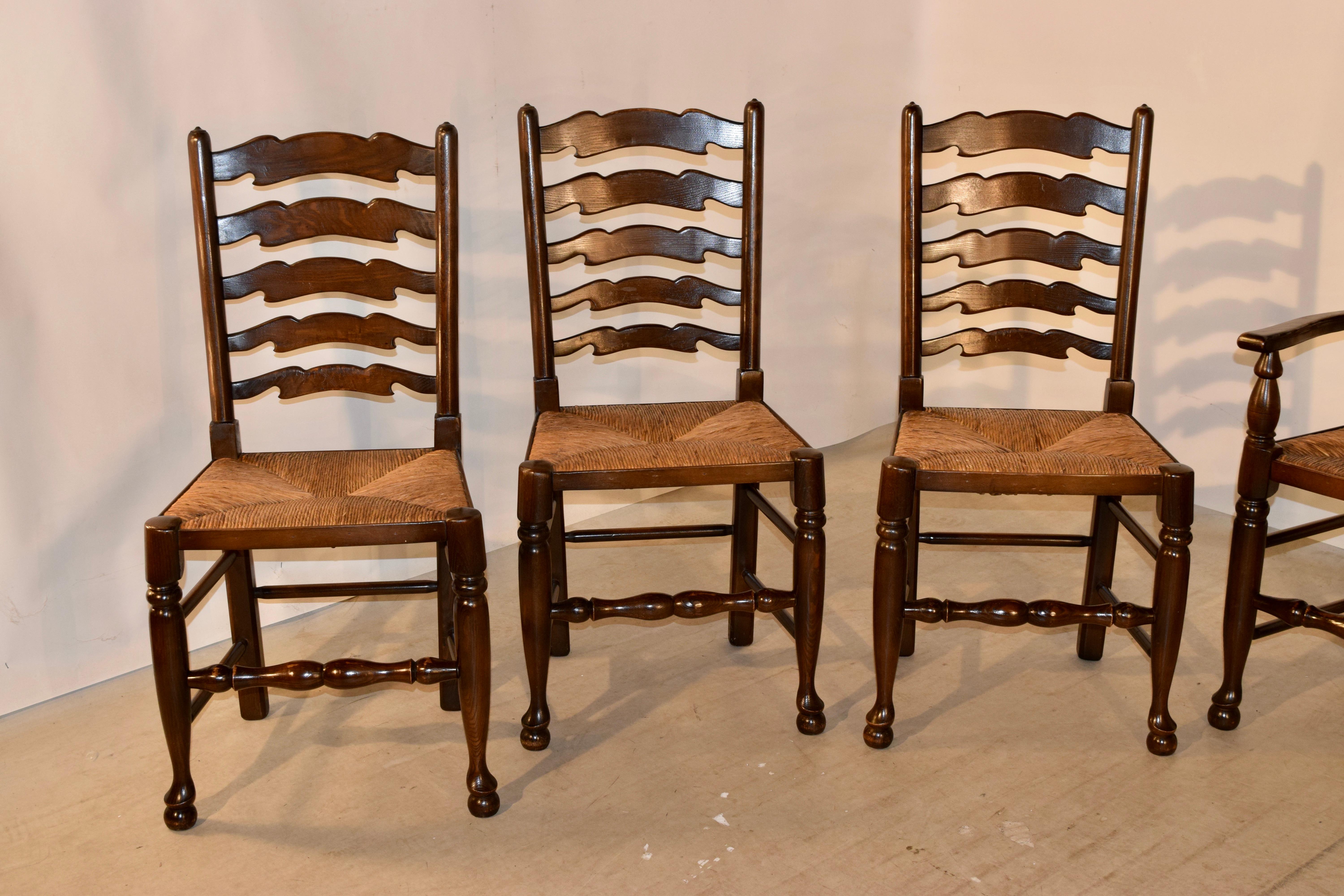 Set of eight oak ladder back chairs from England with woven rush seats, circa 1960-1970. There are two armchairs and six side chairs. Handmade. The arm chairs measure 22.25 W x 21 D x 41.75, with a seat height of 18.25 inches.