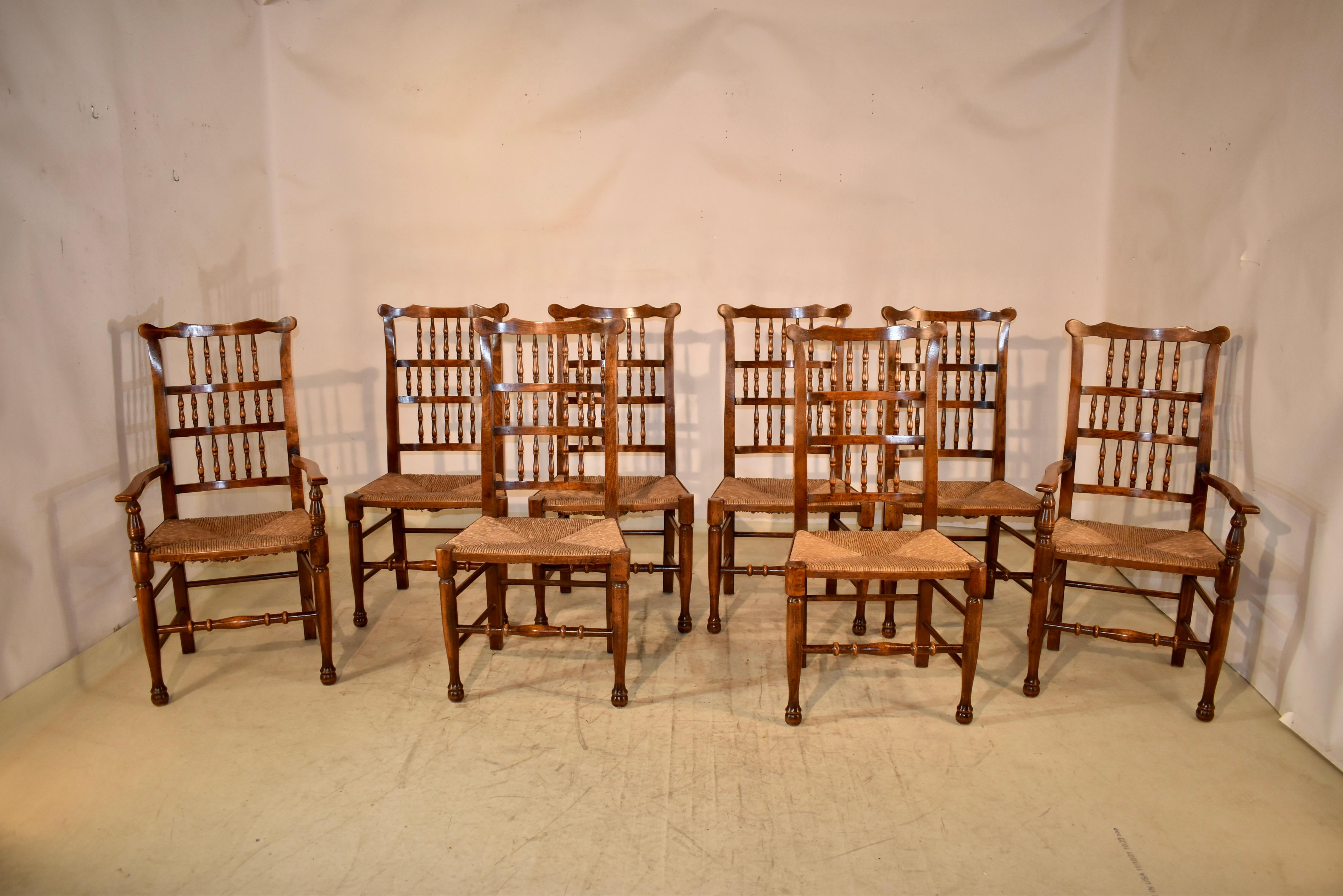 Set of eight ash spindle back chairs from England with woven rush seats, circa 1920. There are two armchairs and six side chairs. The set of chairs are a wonderful form and are made from rich colored ash wood.  The backs have ears at the top, and