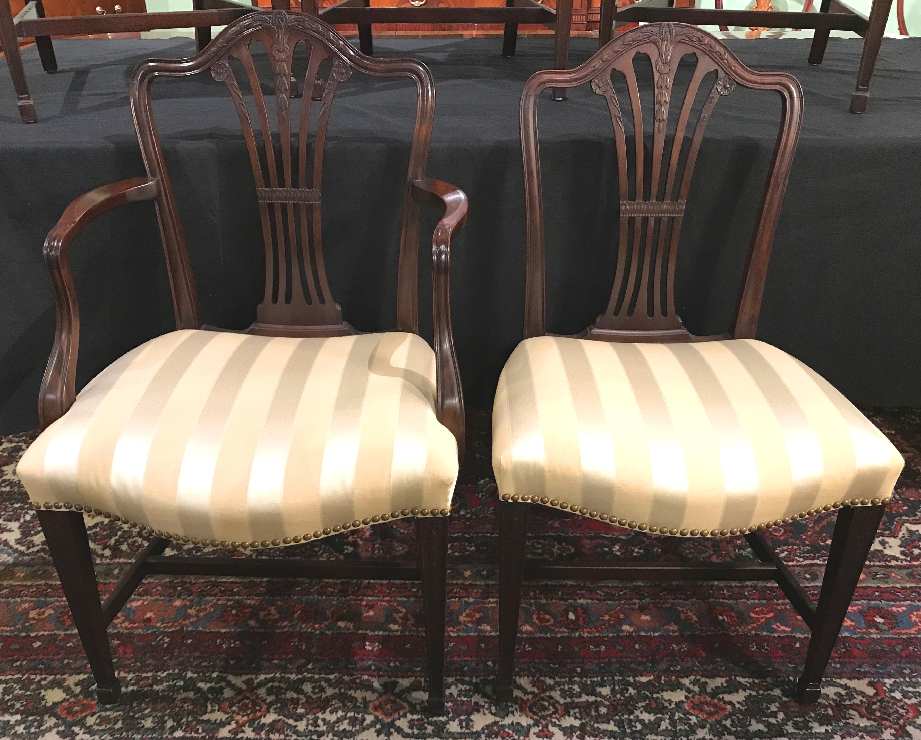 A fine custom set of six solid carved mahogany dining chairs, consisting of two armchairs and four side chairs, with bellflower carved decoration and striped satin upholstery, in very good overall condition, with minor imperfections and expected