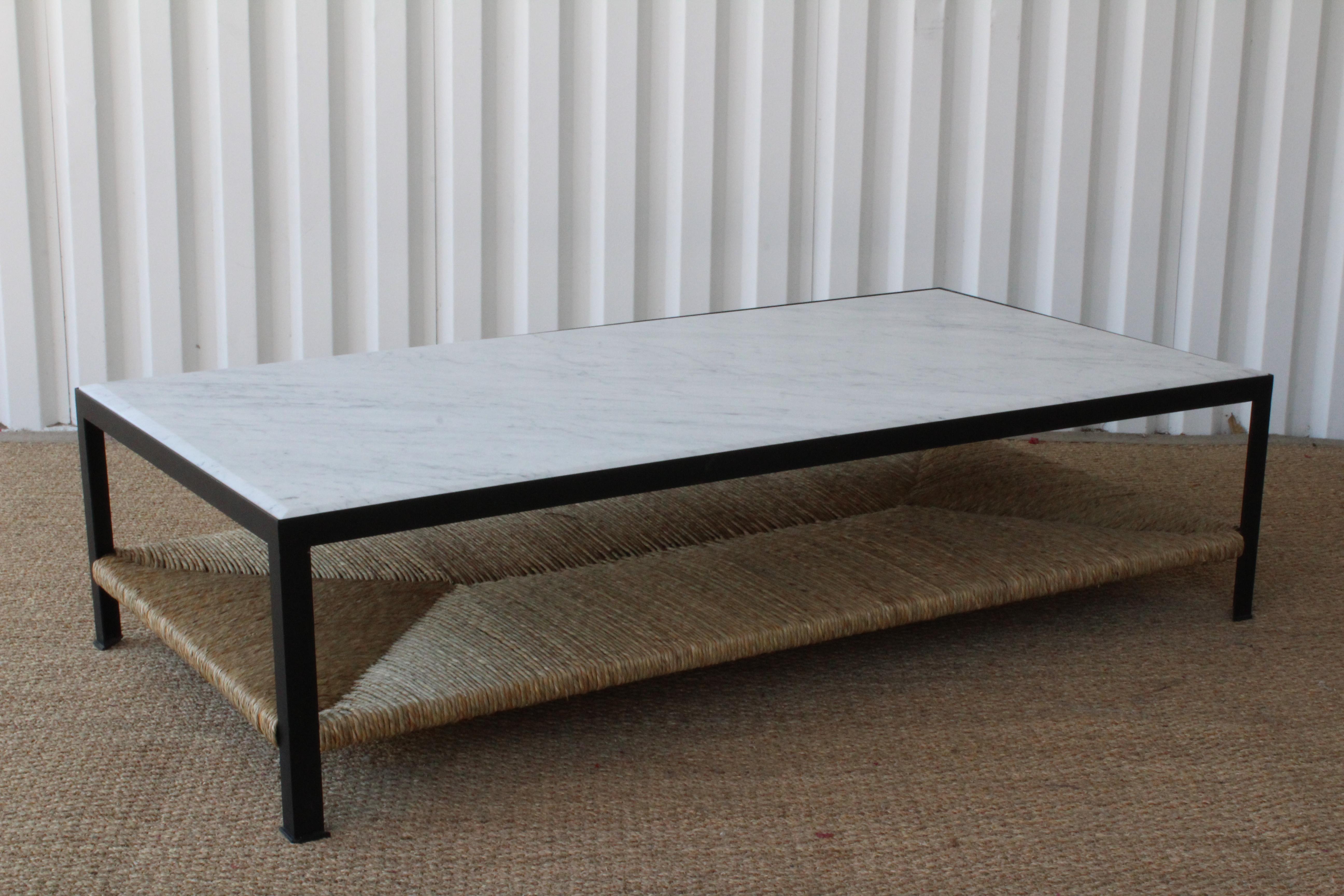 Custom steel framed coffee table with a marble top and handwoven rush shelf. The steel frame has been powder coated black. The marble top features a beveled detail.