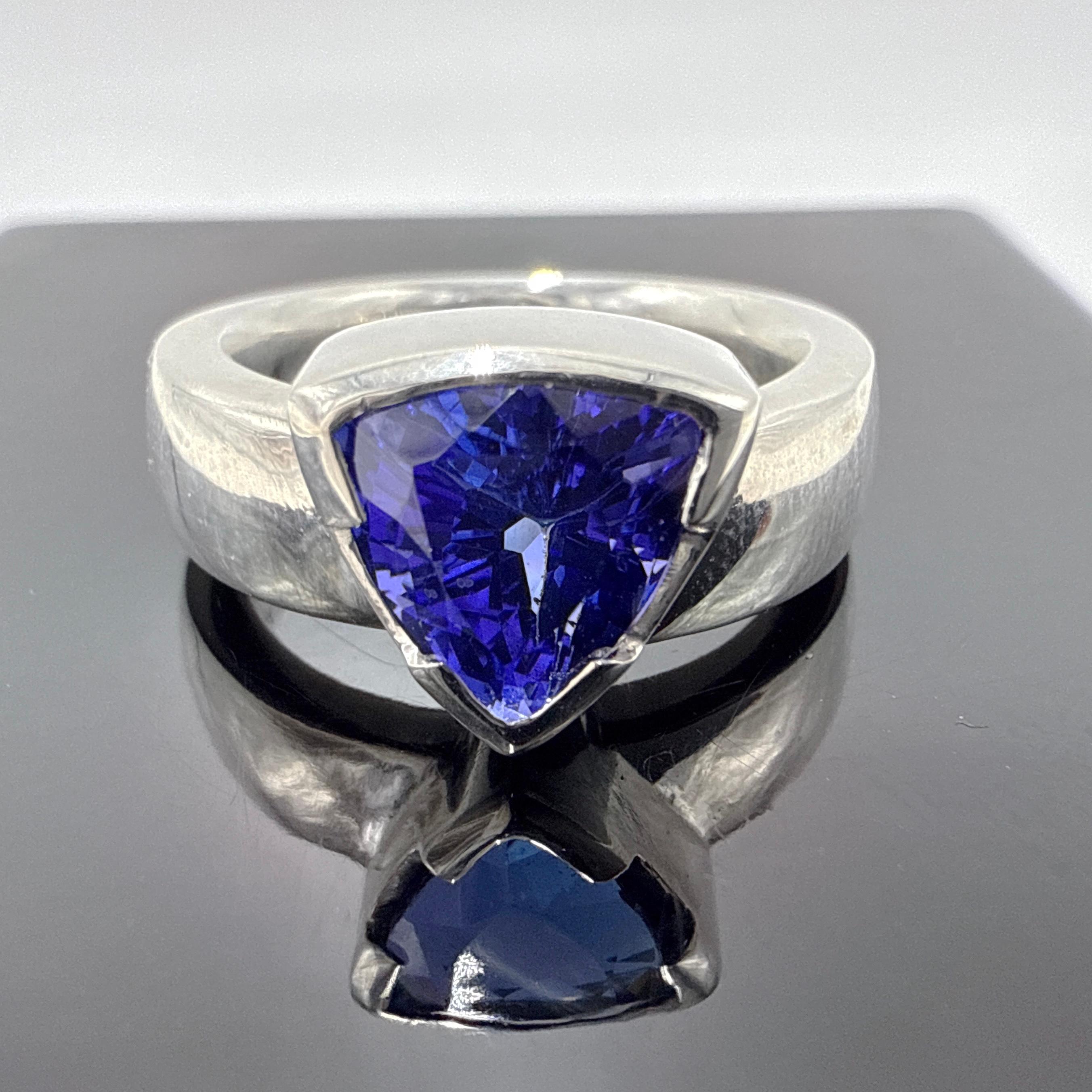 Il s'agit d'une toute nouvelle bague en argent sterling faite à la main et sertie d'une tanzanite triangulaire de 2,71 carats. Le design présente une monture verticale en demi-lune avec des épaules rectangulaires arrondies et une face inférieure