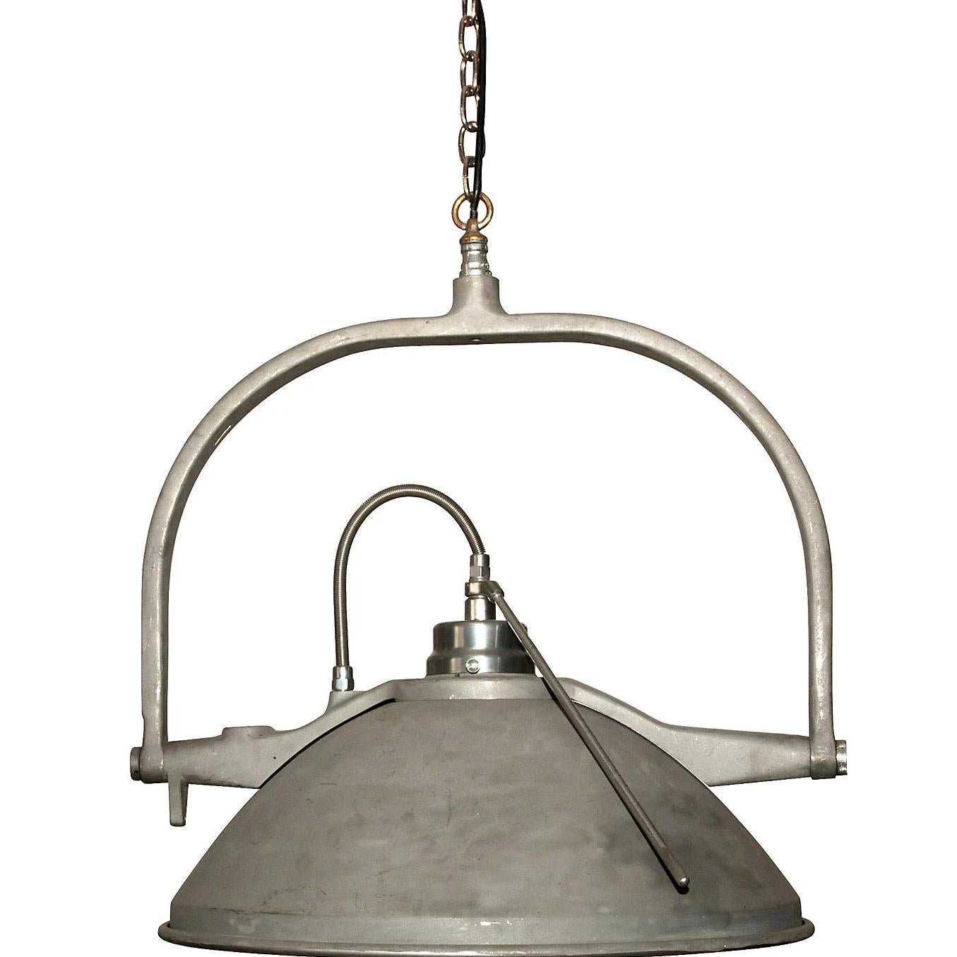 Una grande lampada a sospensione che è stata riutilizzata a partire da lampade per esami medici vintage. Hanno un'inclinazione regolabile e una ciotola pendente a specchio. Sospendi una singola luce su un piccolo spazio da pranzo o nello studio di