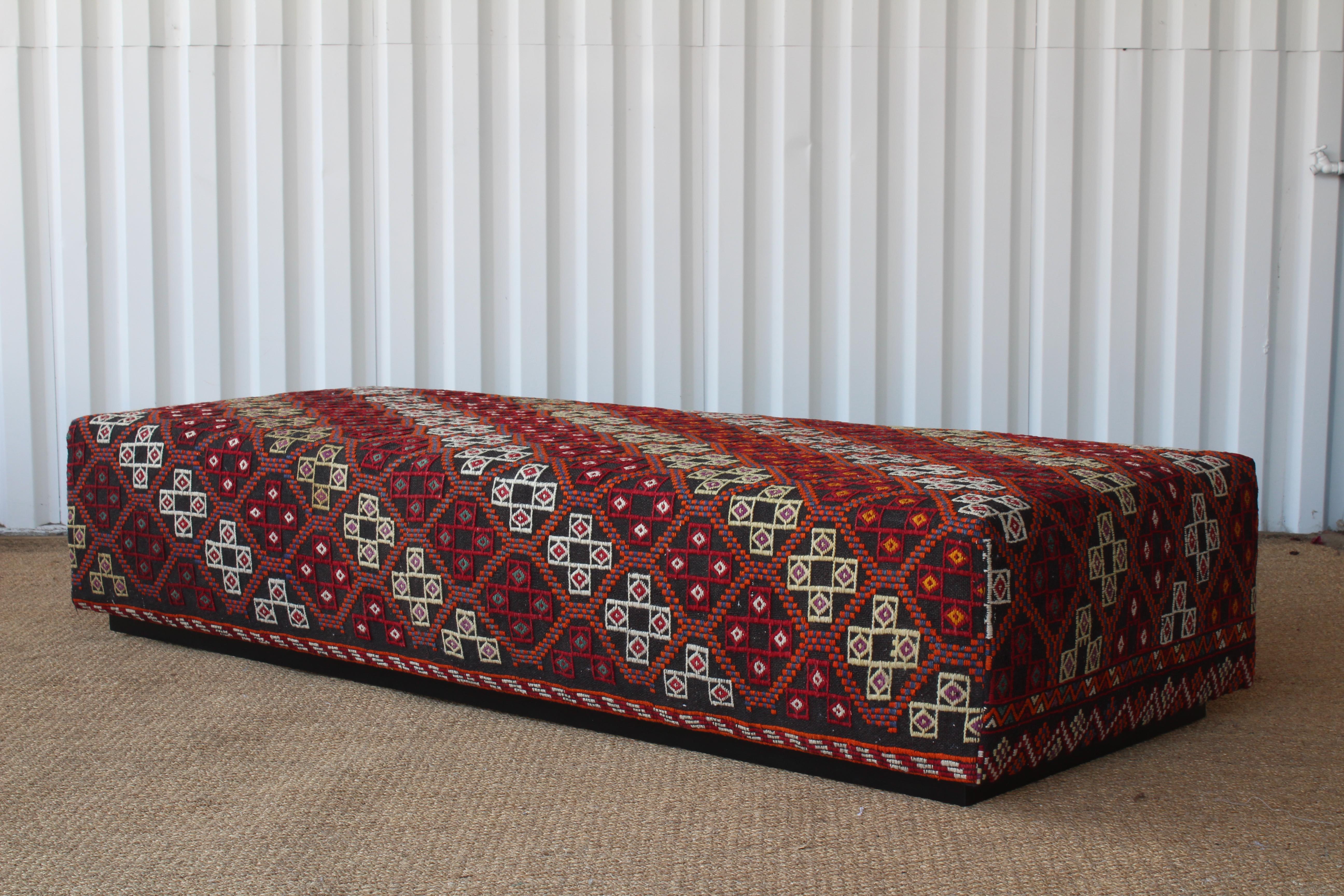 Custom made ottoman upholstered in a vibrant vintage wool Turkish rug from the 1960s. Sits on a satin black wood recressed base.