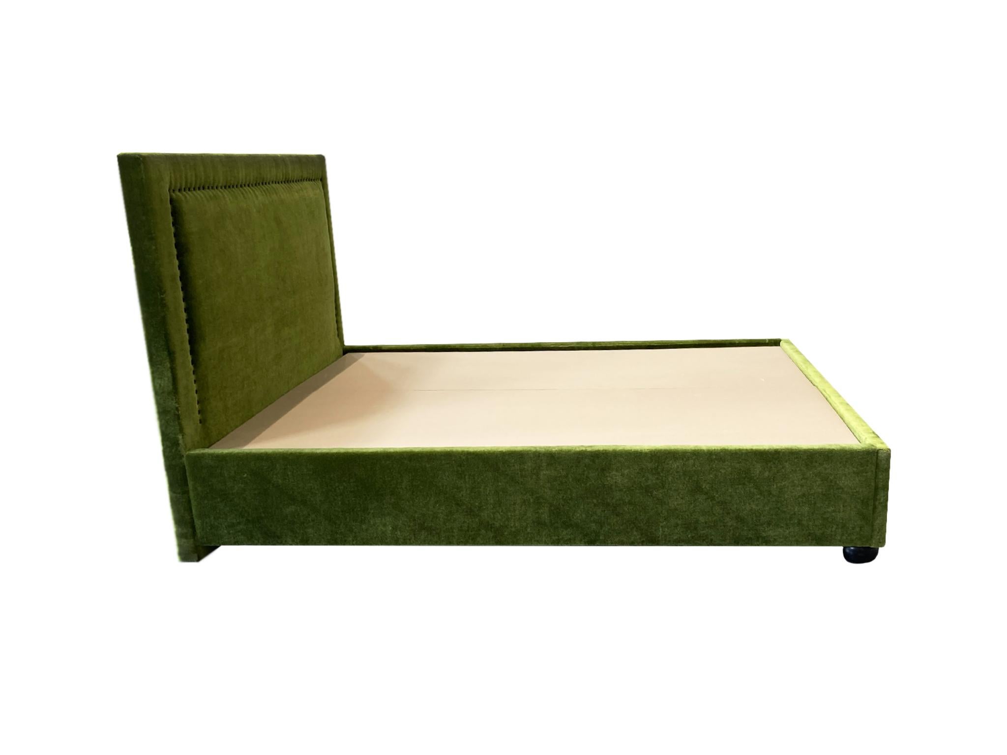 A newly custom-crafted bed-frame for a queen-sized mattress. It is designed in an elegant tuxedo style. The frame consists of 1 headboard, 2 side-rails, and 1 footboard that are all upholstered in a rich moss-green mohair, and 2 fabric-wrapped