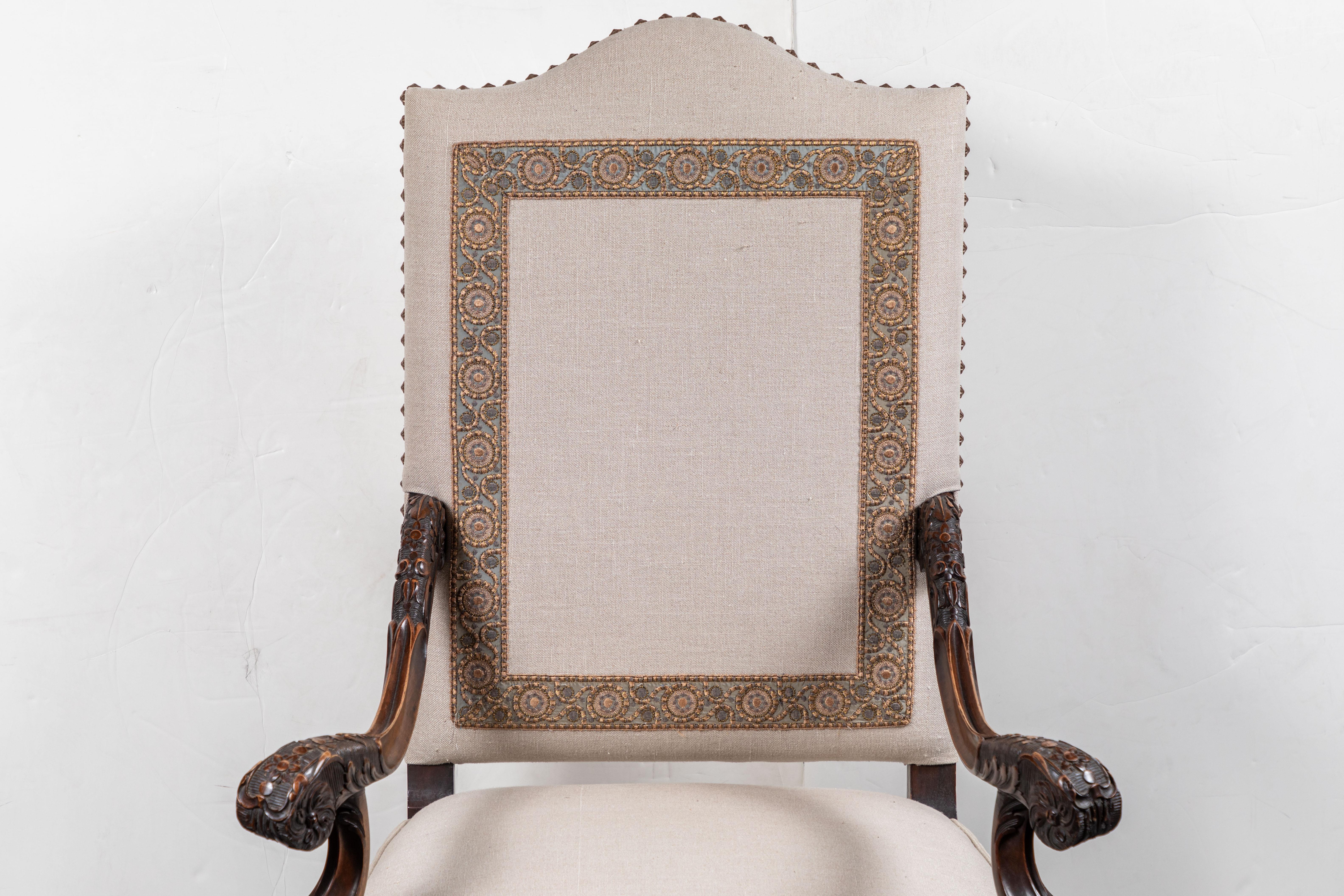 Elegant, splayed arm, hand carved, French, walnut armchair above serpentine legs and stretcher. Upholstered in contemporary neutral linen, with raised nail heads, and featuring a lovely applique back splat with sterling sliver, and 22-karat gold