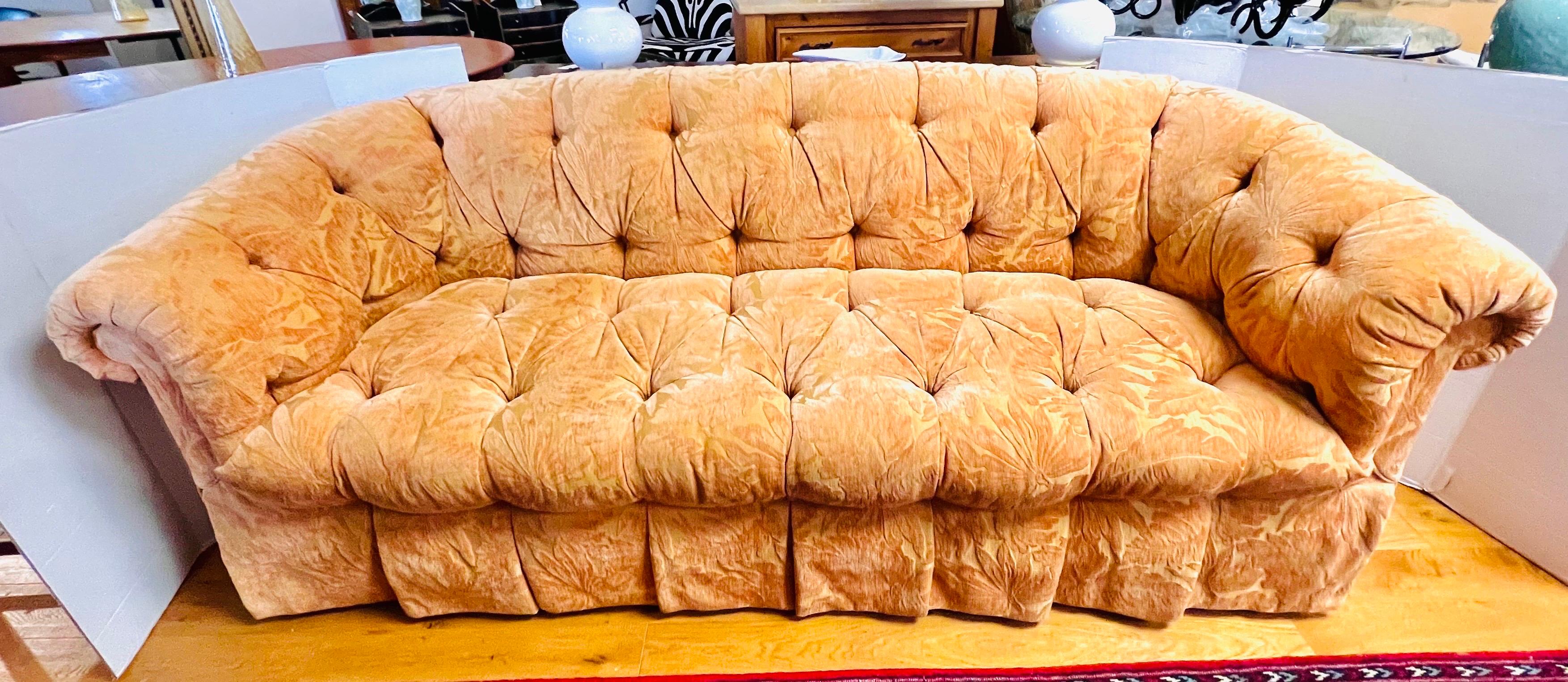 Custom tufted sofa with rolled arms and pleated skirt which is upholstered in a plush leaf print textured chenille fabric and button tufting on back and seat. The color is an exclusive gold/persimmon color, ultra luxurious looking. Comes with