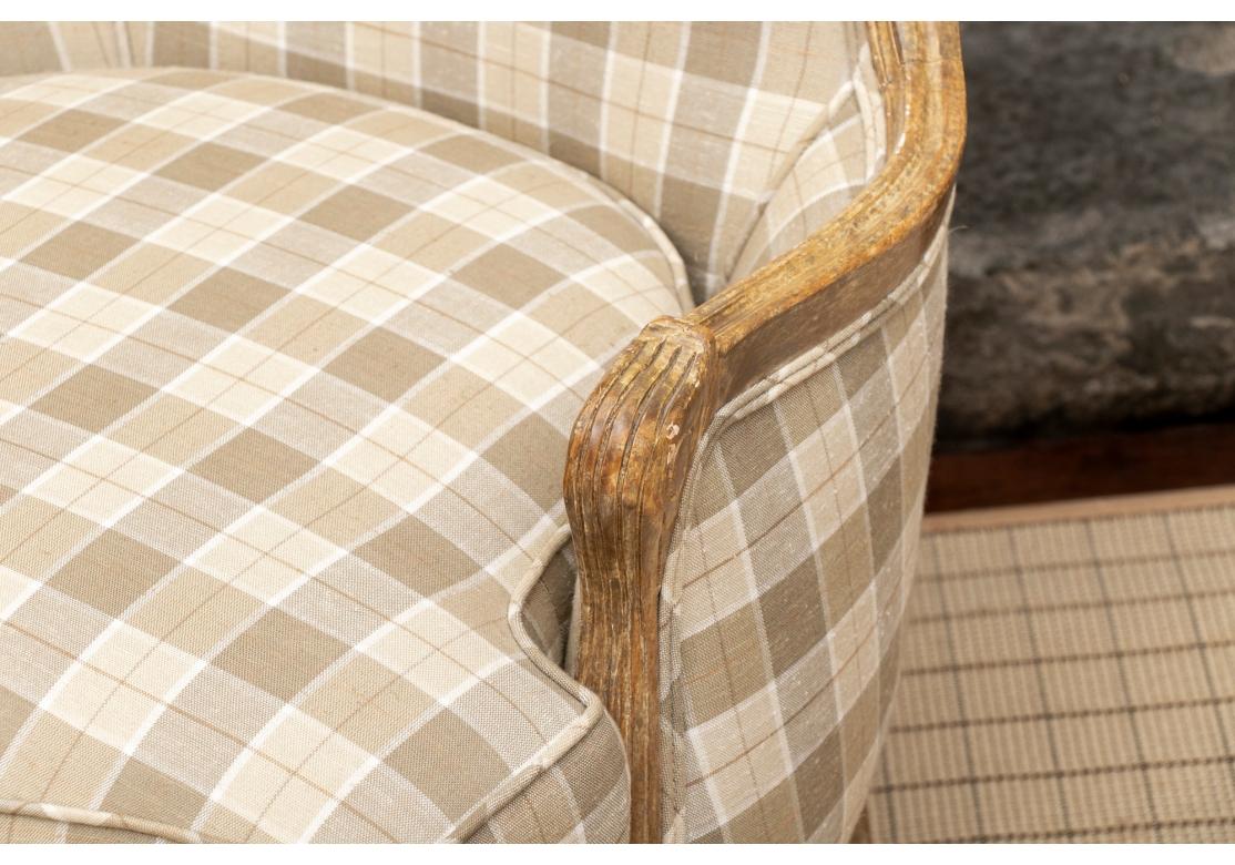 Custom bergere with fixed back, loose pillow seat, faux paint decorated frame with a distressed finish, resting on cabriole legs. Covered in plaid fabric with slight nubby feel and the back in a contrasting striped fabric.
Dimensions: 27 1/2