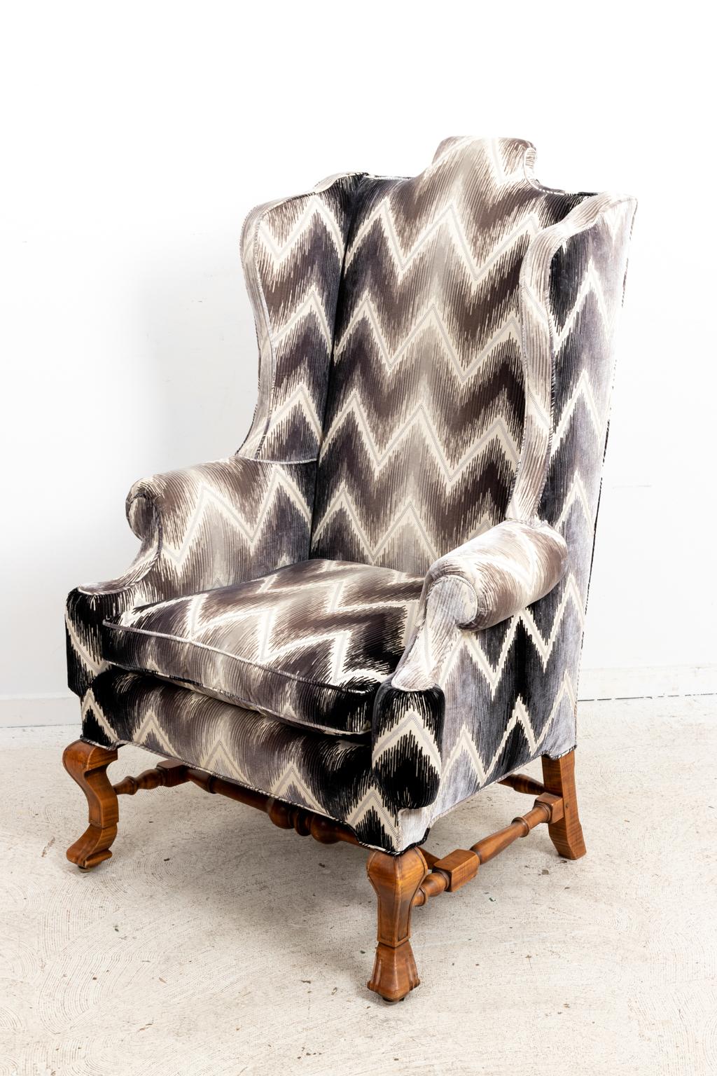 Custom upholstered wing back armchair with carved Spanish scroll feet on cabriole legs. The wingback chair is also constructed on the seat back with a high head rest. Please note of wear consistent with age.