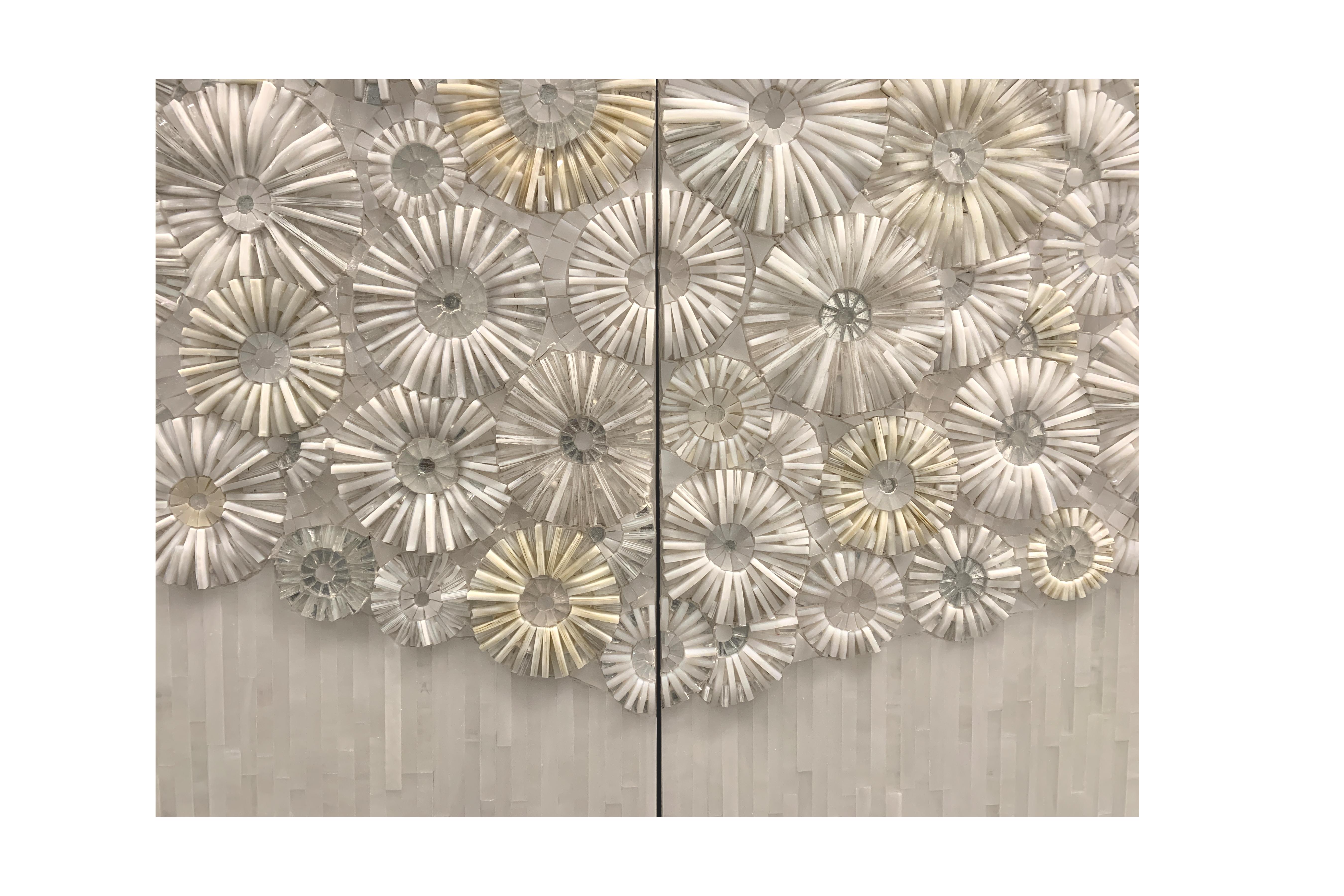 The blossom buffet by Ercole Home has a 4-door front.
Each door is covered in handcut glass mosaic. Decorating the surface in a variety shades of white and ivory the blossom buffet has a floral mosaic pattern. Thin vertical glass strips cover the