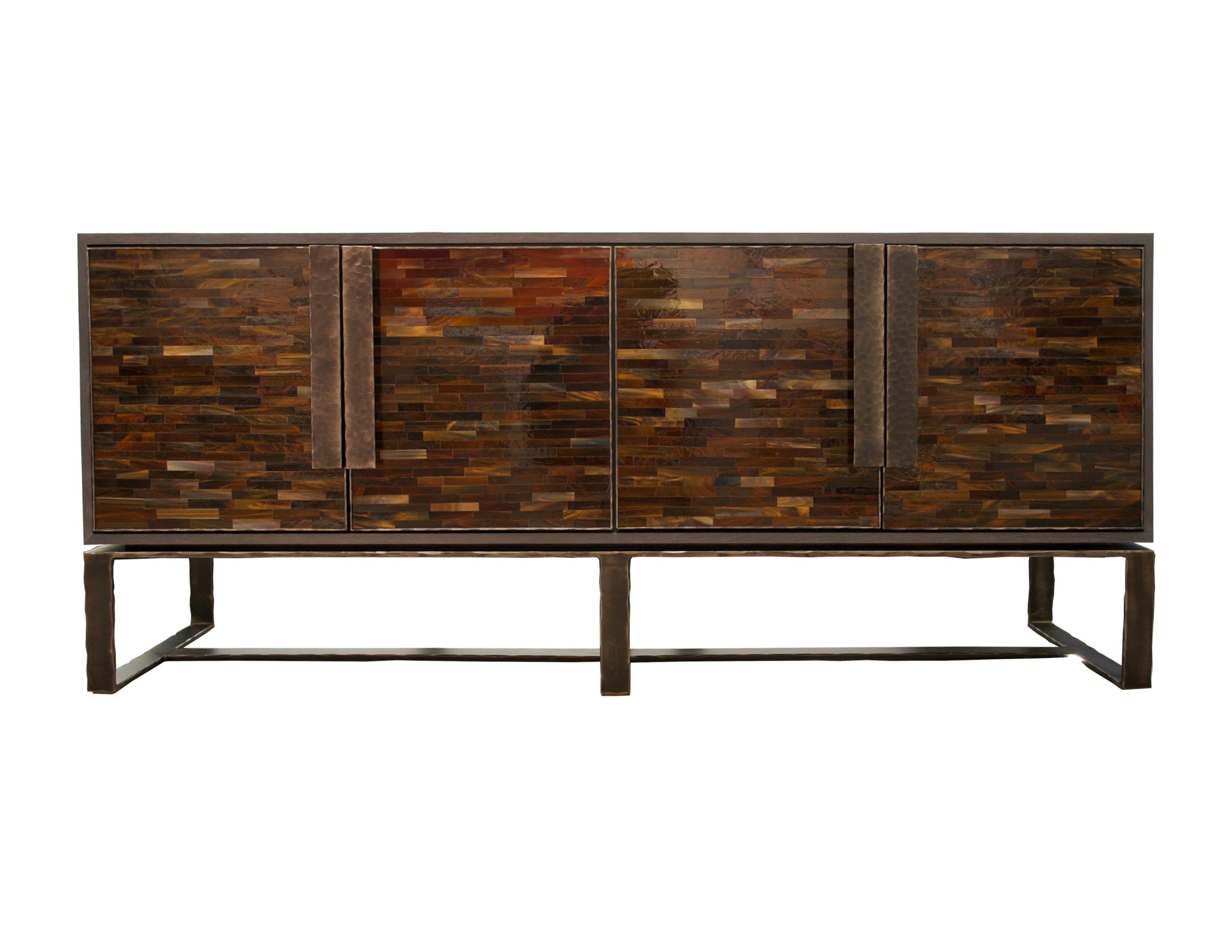 The Chelsea credenza or sideboard by Ercole Home has a 2-door front, with Espresso wood finish on oak.
Handcut glass mosaics in medium and dark chocolate decorate the surface in Luis pattern.
Hand-hammered metal framed doors, handles, and base in