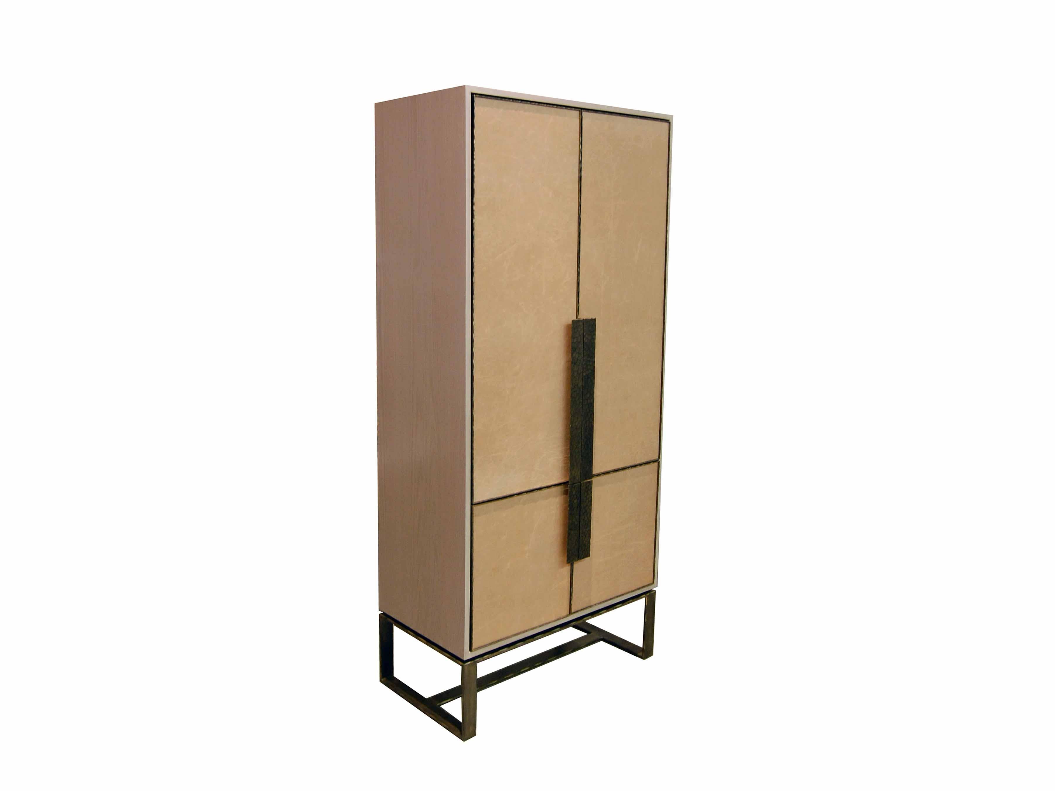The Chelsea bar cabinet by Ercole Home has a 4-door front, with sand wood finish on oak.
Hand-stretched leather in sand brown decorates the door fronts.
Hand-hammered metal framed doors, handles, and base in dark bronze metal finish.
The cabinet