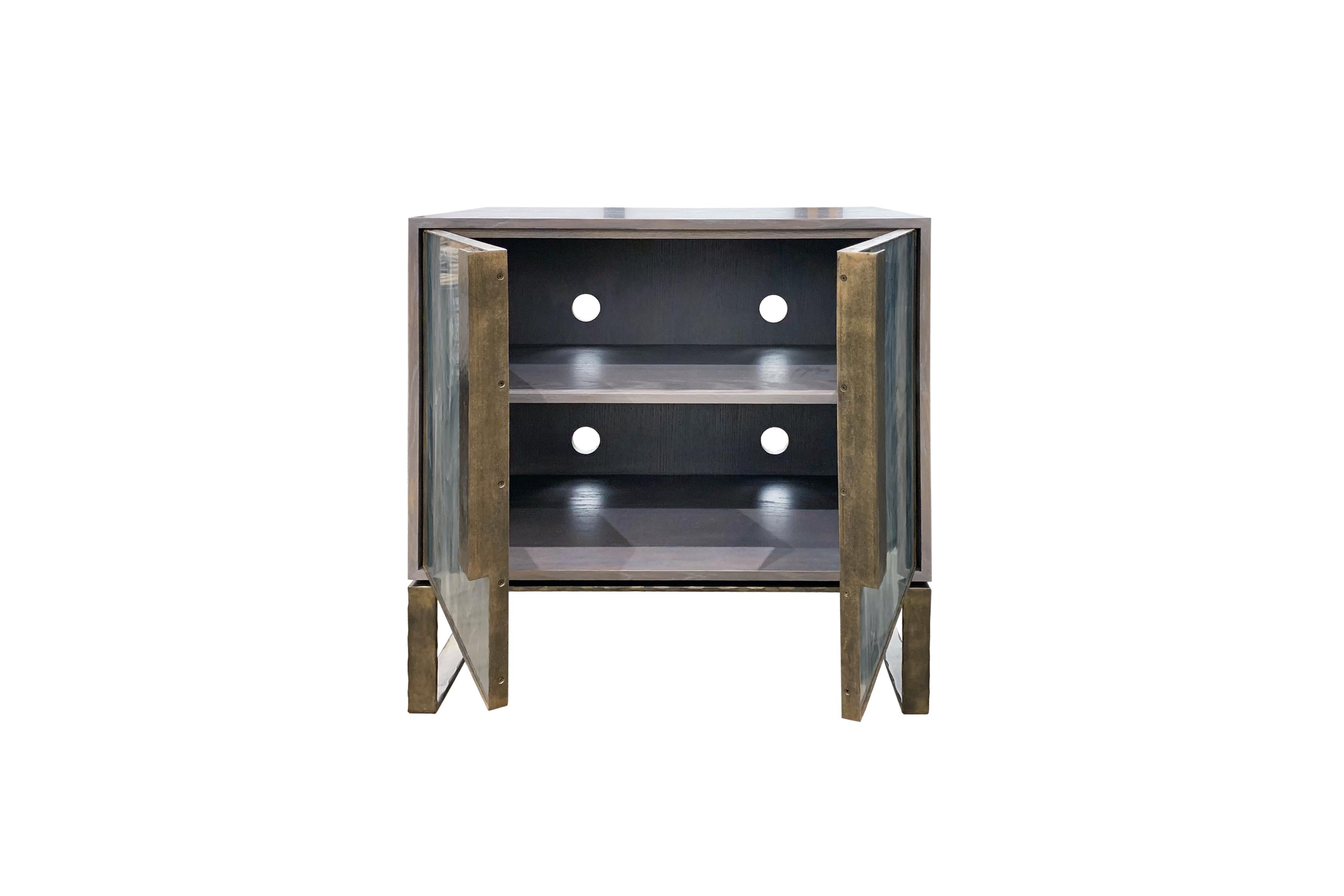 This chelsea buffet or sideboard by Ercole home has a 2-door front, with Earl Gray Ceruse wood finish on oak.
Handcut glass panels in Wispy Gray Silver are on the door surface.
Hand-hammered metal framed doors, handles, and base in dark bronze metal