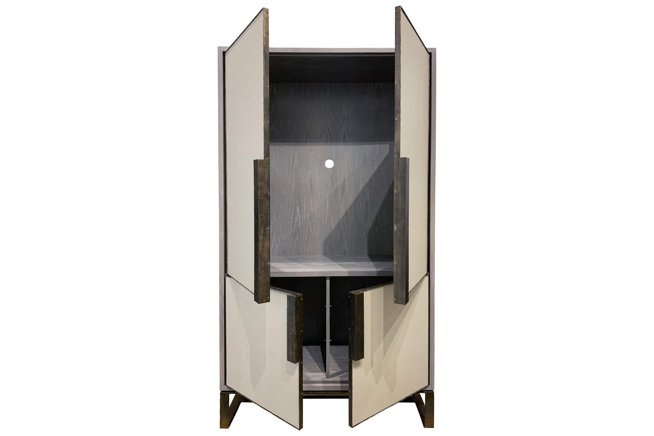 The Chelsea bar cabinet by Ercole Home has a 4-door front, with earl gray ceruse wood finish on oak.
Hand-stretched leather in Polis gray decorate the door fronts.
Hand-hammered metal framed doors, handles, and base in Dark Bronze metal
