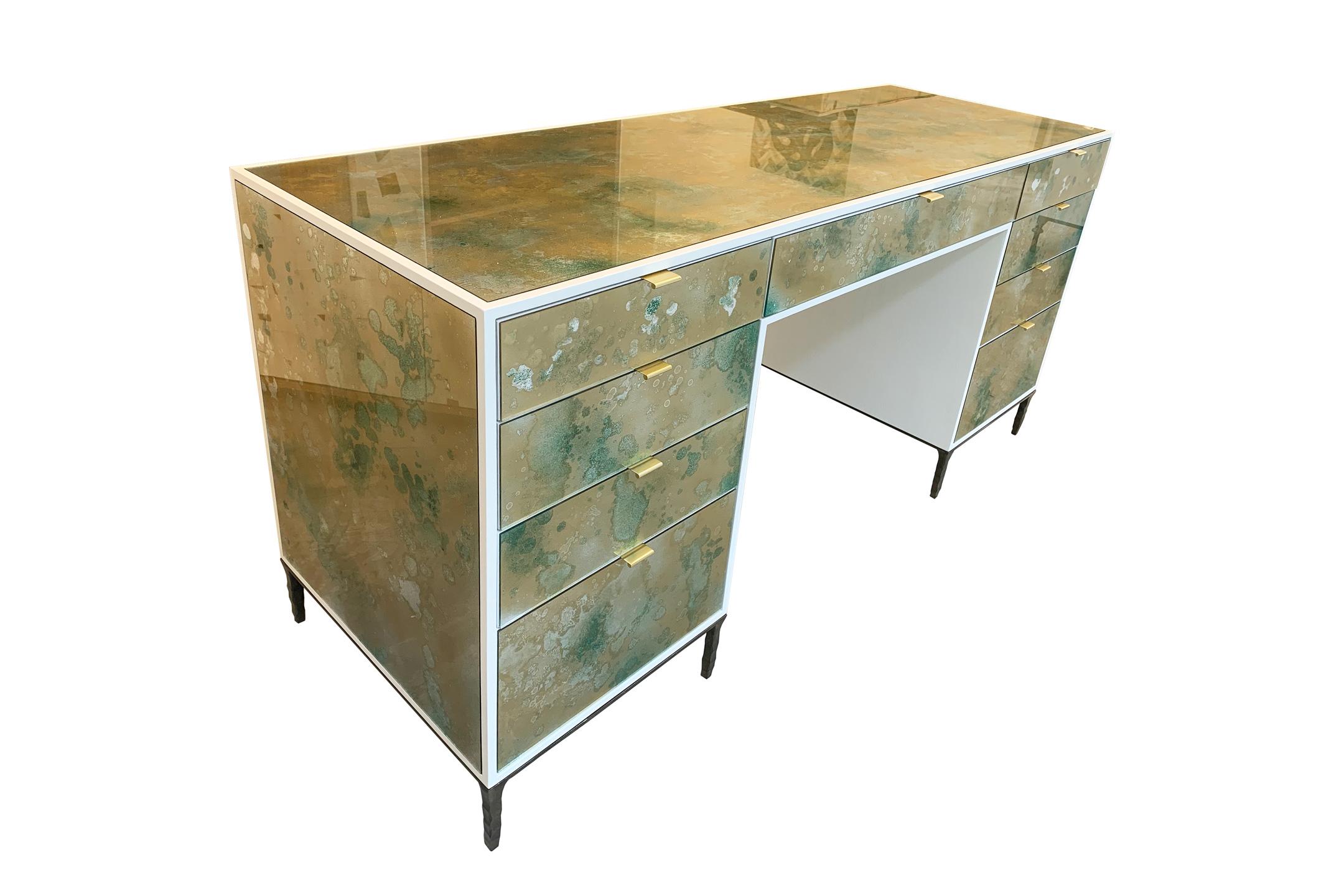 The Mystic Byzantine Gold Green vanity by Ercole Home has a 9-drawer, with ivory wood finish on oak. Hand painted eglomise glass panels are inset on the surface.
There are nine pulls in brushed brass finish.
The hand hammered metal base is in