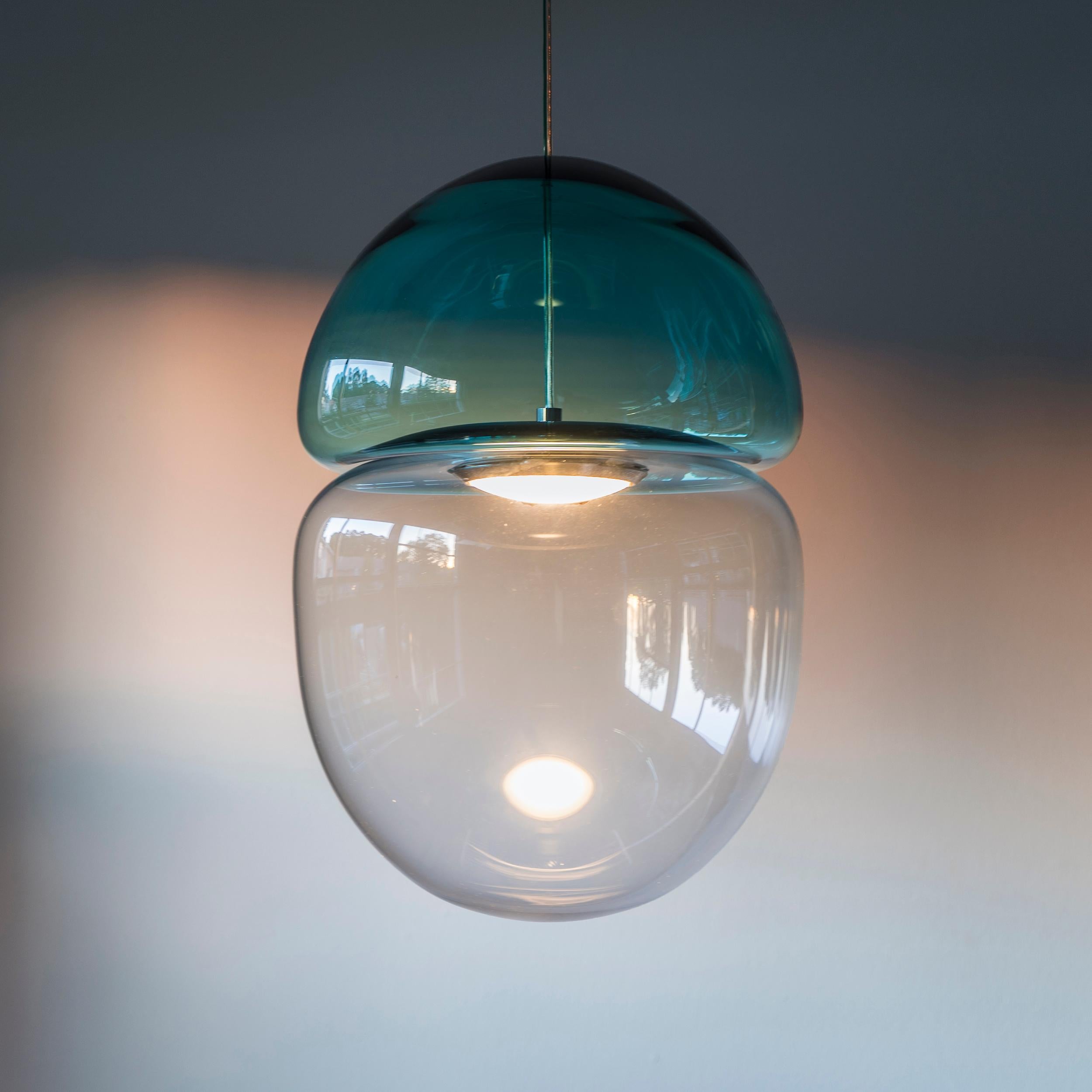 Dew and drop is a pendant lamp made of two pieces of hand blown glass, resembling a dewdrop resting on top of a falling droplet of water. The light is trapped in between the glass, creating natural shades and reflections all around.

The dew and