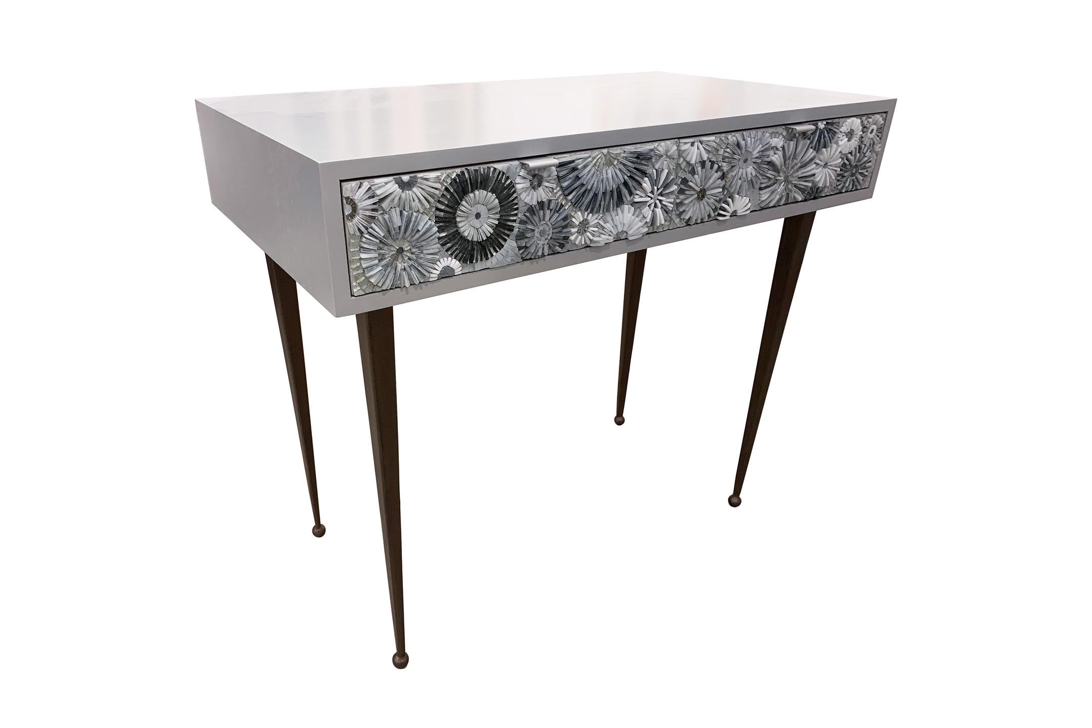 Le bureau/lavabo Pavia Blossom d'Ercole Home comporte 2 tiroirs, avec une finition en bois gris ciel sur chêne.
Des mosaïques de verre bleu-vert et turquoise taillées à la main décorent les façades des tiroirs dans un motif blossom (fleurs en trois