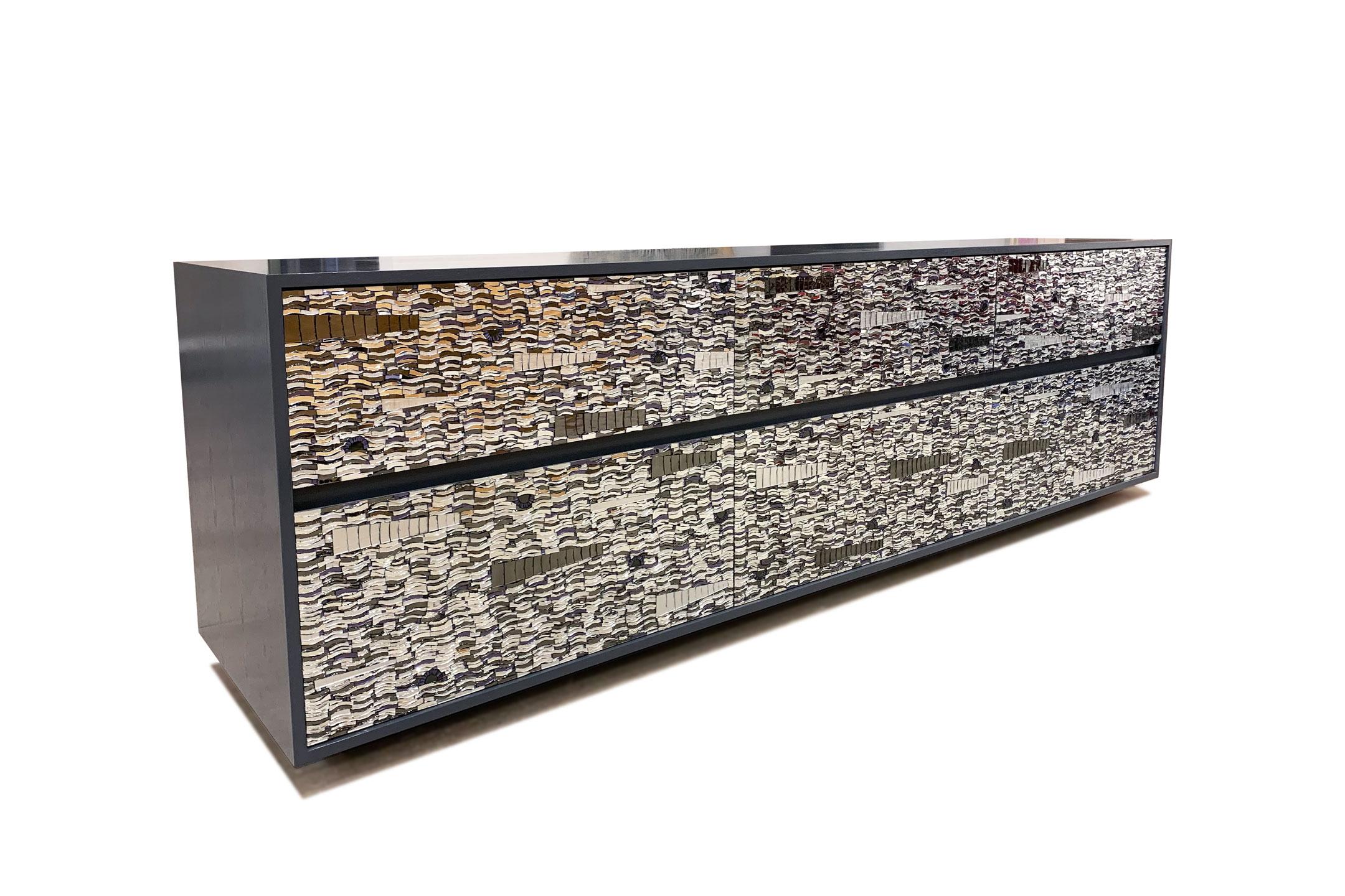 The Ravenna chest by Ercole Home has a 6-drawer front, with 2-3/8 H platform wood base.
Handcut glass mosaic in grey mirror, silver, mirror, and purple mirror decorate the surface in Ravenna Mosaic pattern.
Dark gray Lacquer wood finish on