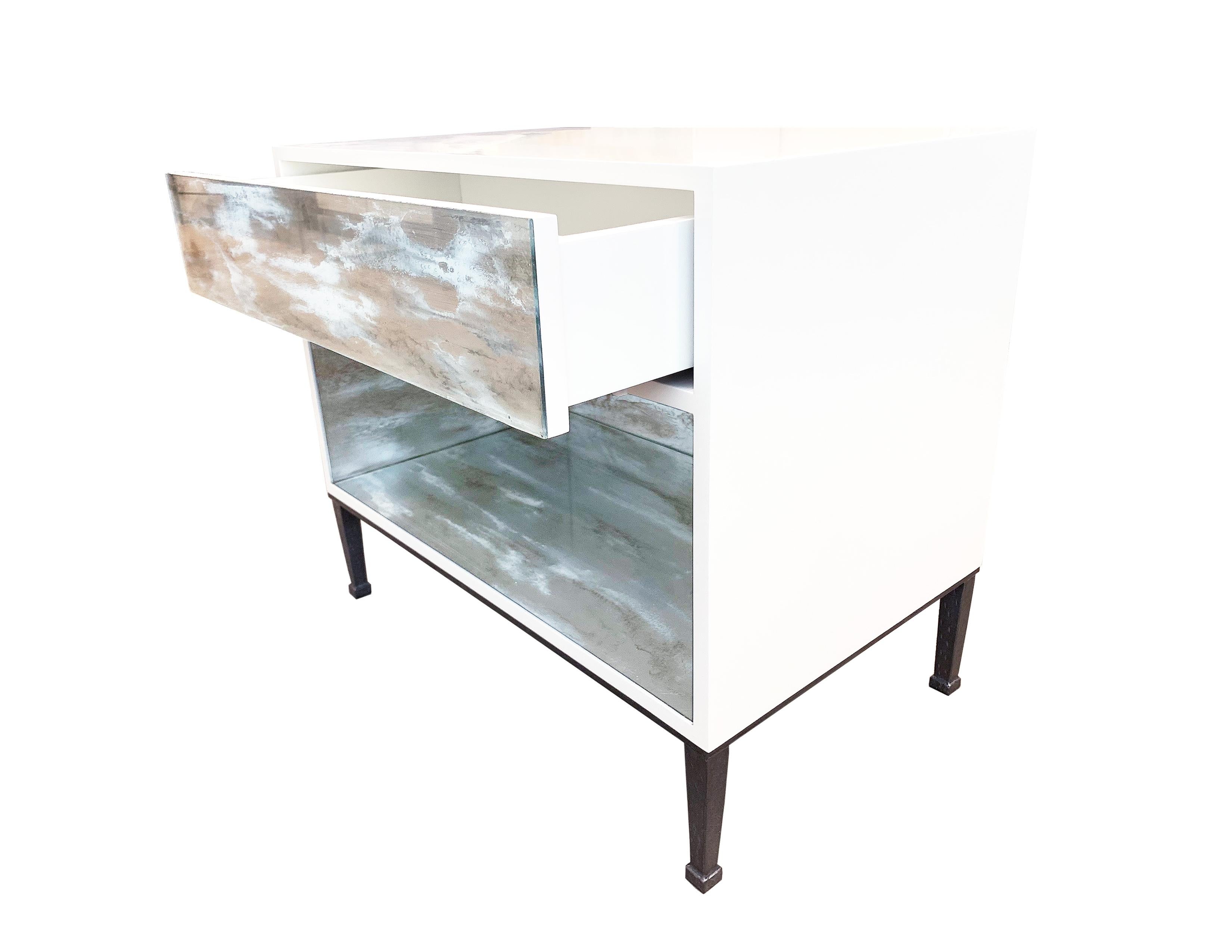 The industrial nightstand by Ercole Home has one drawer front, with white lacquer wood finish.
A hand painted glass panel in Galaxy decorates the surface of the drawer and open shelf.
The industrial metal base is in Pewer finish.
The drawer with