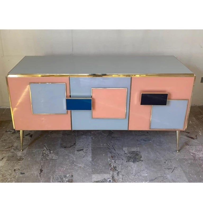 Bespoke customizable 3-door modern cabinet sideboard, entirely handcrafted in Italy with Memphis inspiration for the attractive colorful deconstructed geometric decor with raised pattern and handles. The surround is decorated with art glass in