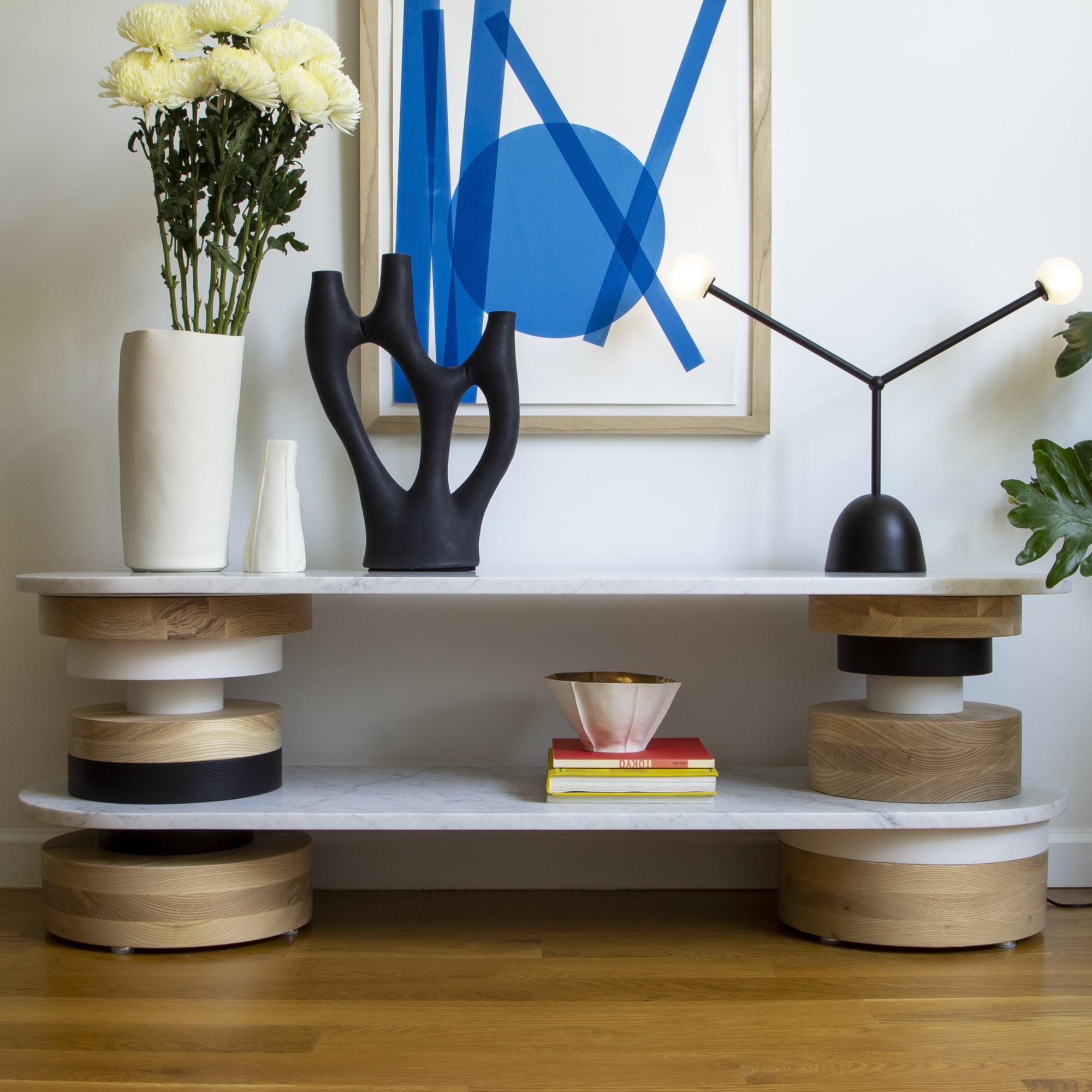 The Sottsass-inspired “Sass Console Table” is a bold, graphic statement piece. A honed Carrara marble top sits on an Amish-made base composed of painted and stacked wood circles. Made to order.

The version as shown in the first image is 18