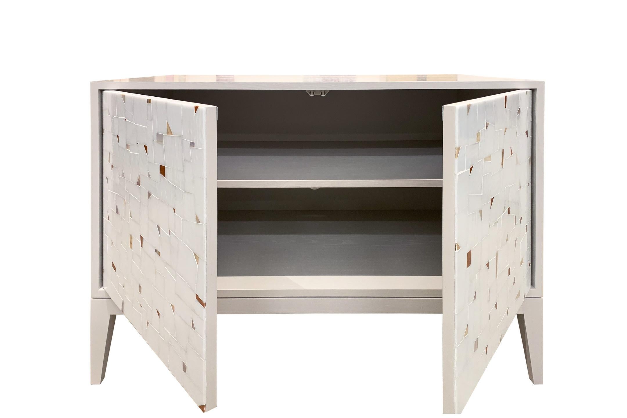The platform buffet by Ercole Home has a 2-door front, with a Misty gray finish on oak. Handcut glass mosaics in Icy white and brown mix glass mosaic decorate the surface in a continuous Terrazzo pattern.
There is one adjustable interior shelf in