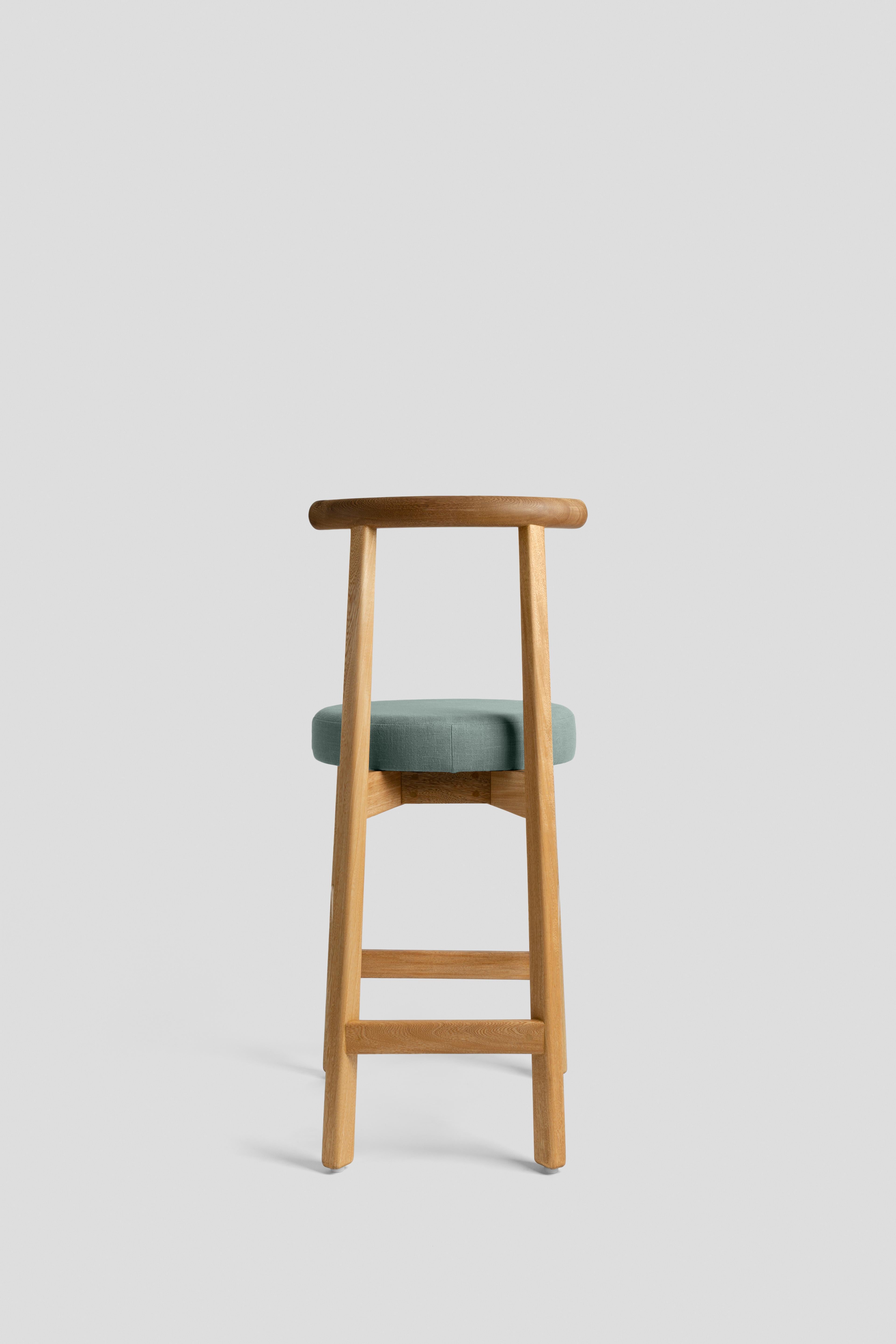 This stool comes from one of our best-selling pieces: the Colima chair. Available in two
different versions, this stool is ideal for the kitchen bar or a perch table. Made of solid wood with fabric upholstered seat, you can have many different
