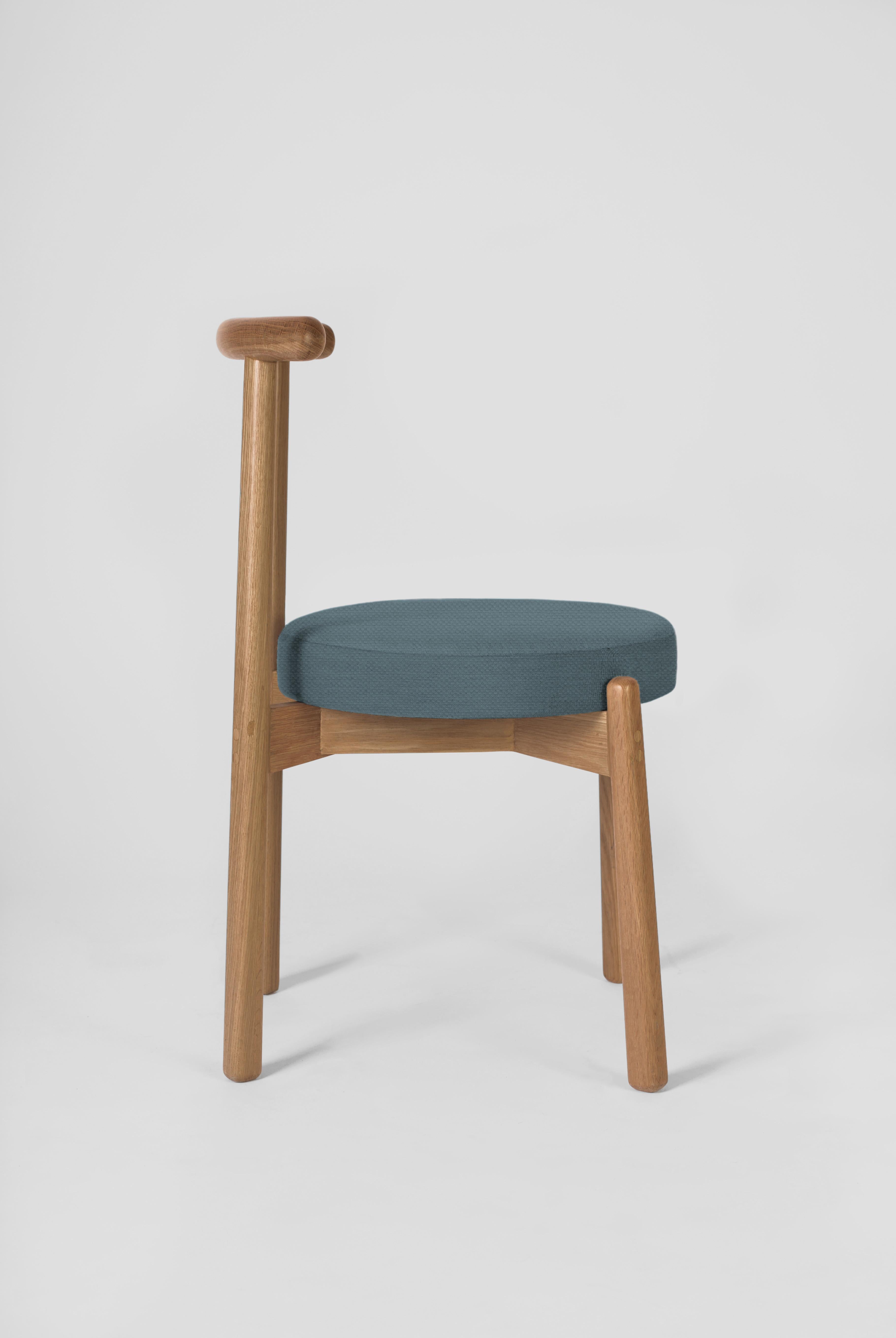 Die Schlichtheit dieses Designs macht diesen Stuhl zu einem vielseitigen Möbelstück, das zu verschiedenen Esstischen und Räumen passt. Die Struktur ist aus massivem Eichenholz gefertigt. Die Kissenbezüge können auf Anfrage gemäß den Katalogoptionen