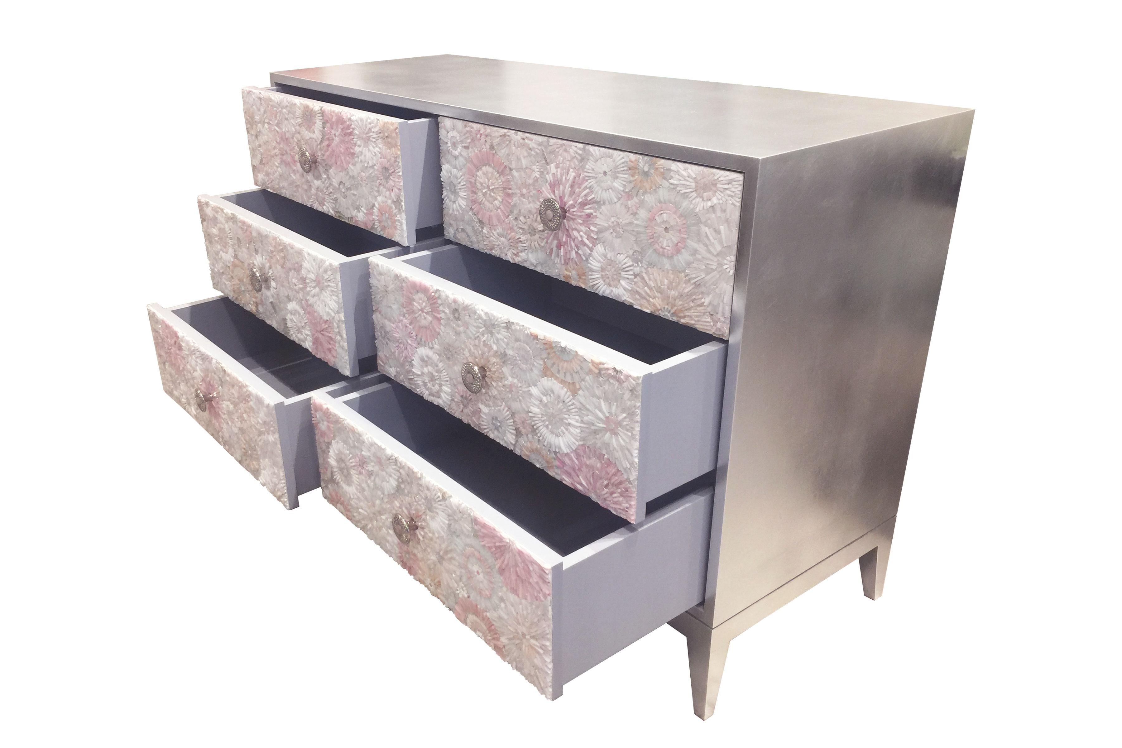 The blossom chest of drawers by Ercole Home has a 6-drawer front, with silver leaf finish on wood.
handcut glass mosaic in variety shades of white and pink decorate the surface in Blossom patterns.
The decorative solid brass pulls in nickel finish