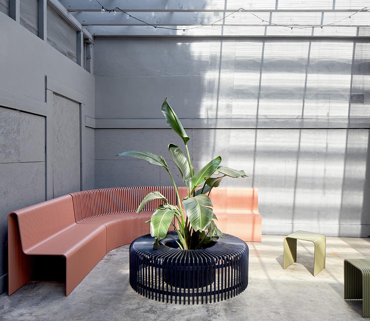 In the Ribbon outdoor bench, layered aluminum tubes stack together to form a circular semi-solid array, with an empty space in the center that can accommodate an optional plant. The bench is offered in five standard colors, but can be color-matched,