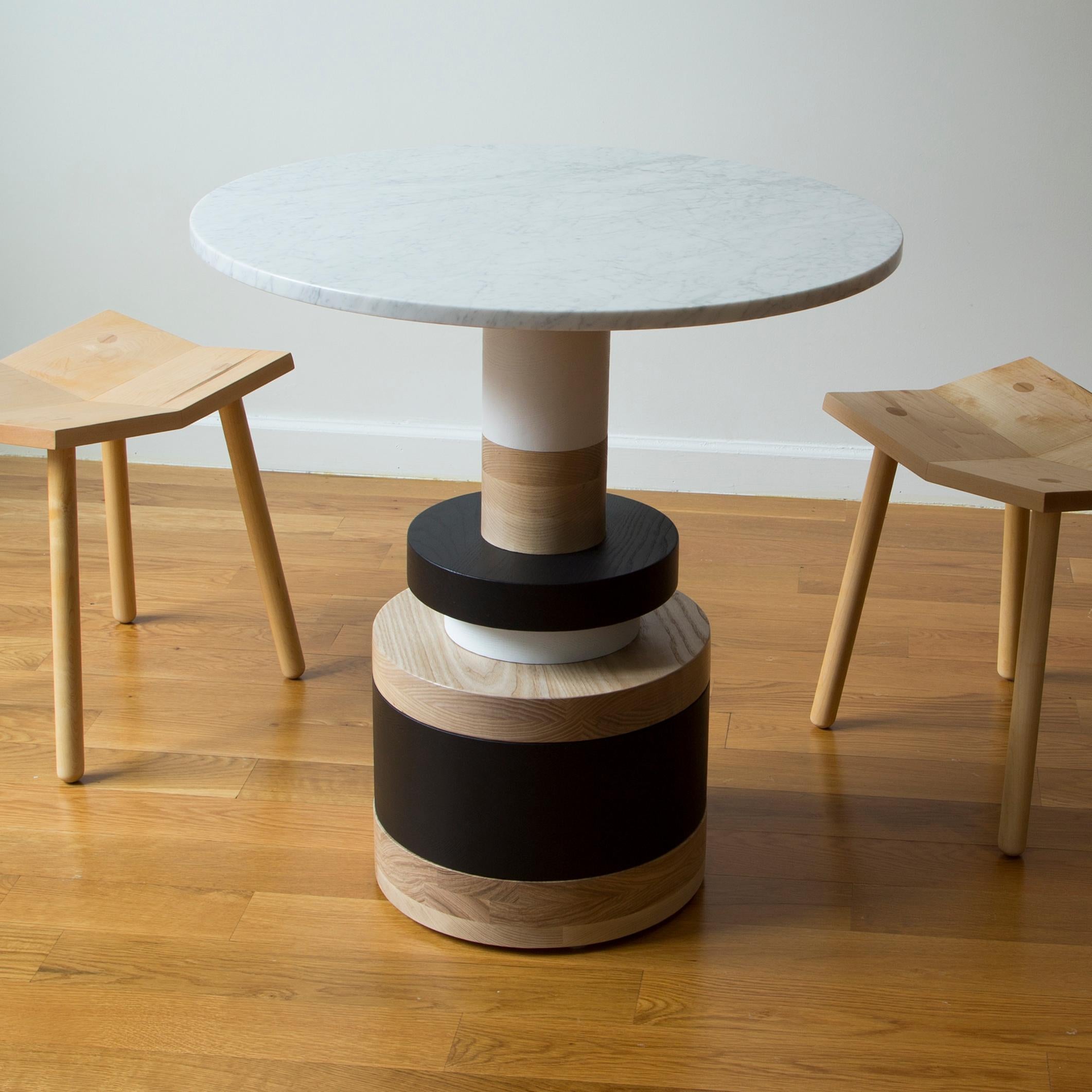 The Sottsass-inspired “Sass Dining Table” is a bold, graphic statement piece. A polished Nero Marquina marble top sits on an Amish-made base composed of painted and stacked wood circles. 

The version as shown is 30