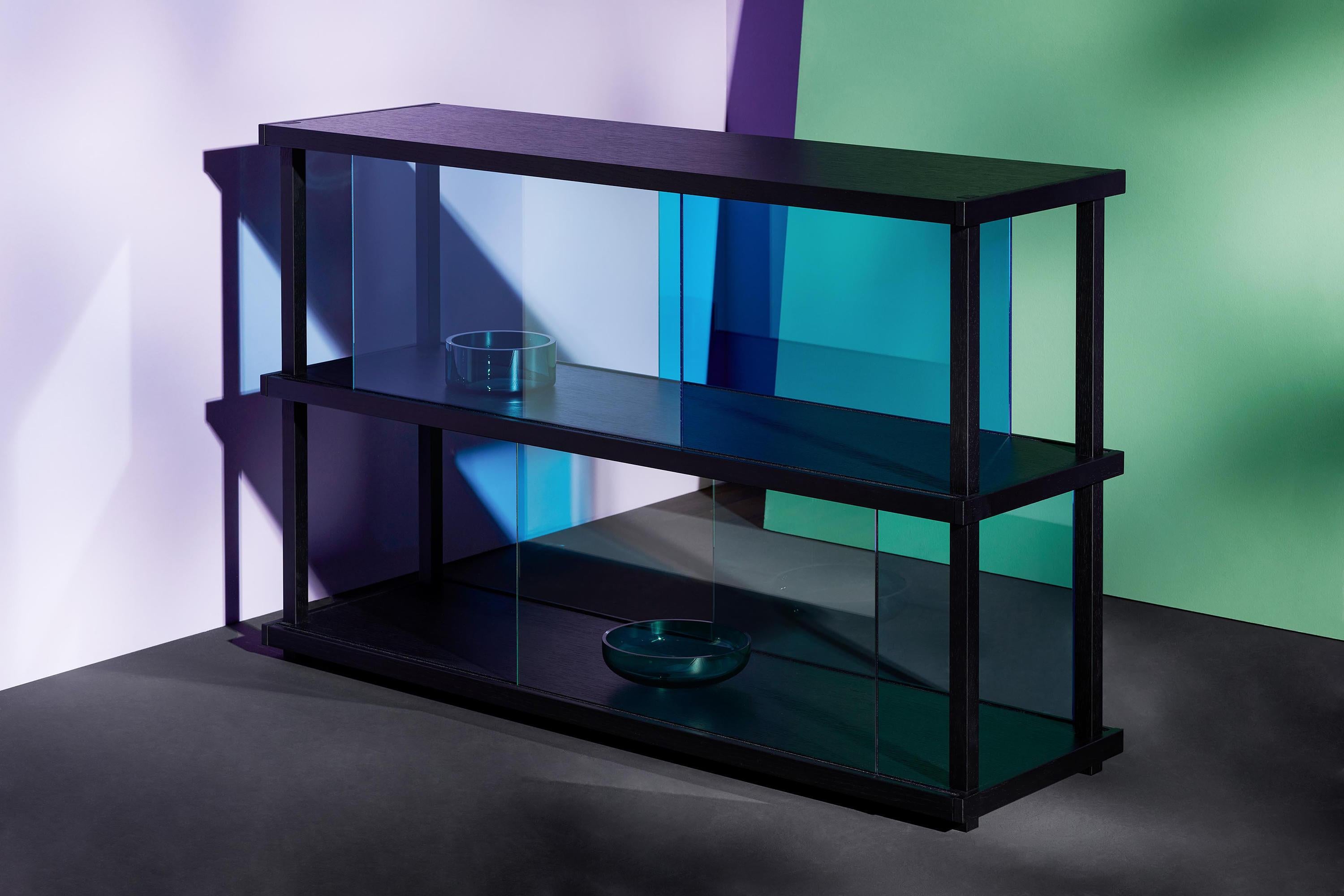 Le linee nette e i rettangoli colorati della libreria CORES ricordano i dipinti di Piet Mondrian. Nella versione progettata per essere posizionata contro una parete, gli inserti in vetro scorrevoli sui frontali delle mensole creano accenti di colore