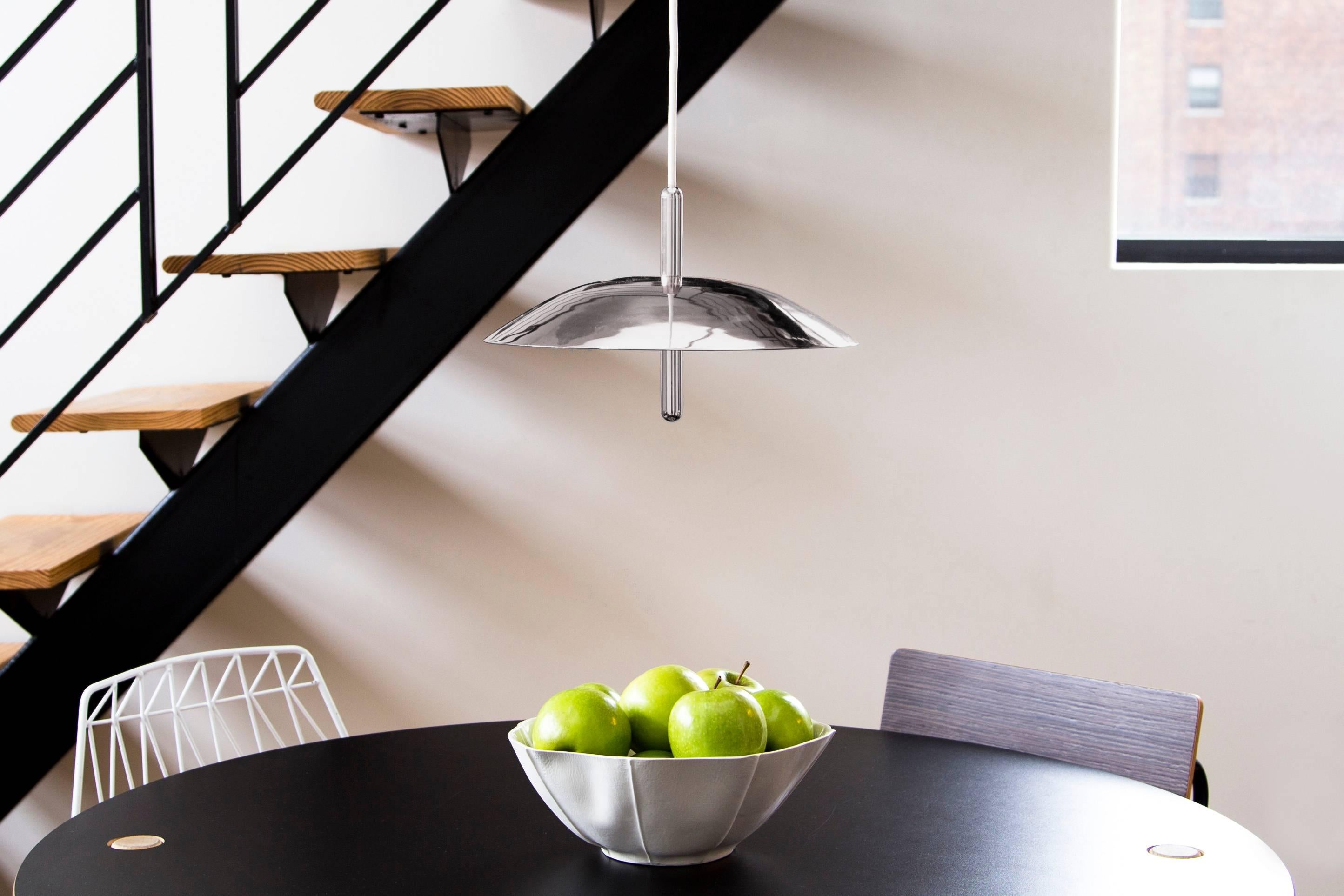 Utilizzando LED caldi e luce indiretta, i pendenti di segnalazione si librano sopra ogni interno come un corpo celeste che emette una luce confortante. Composto da un paralume in metallo filato trafitto da un gambo centrale lucido, il ciondolo