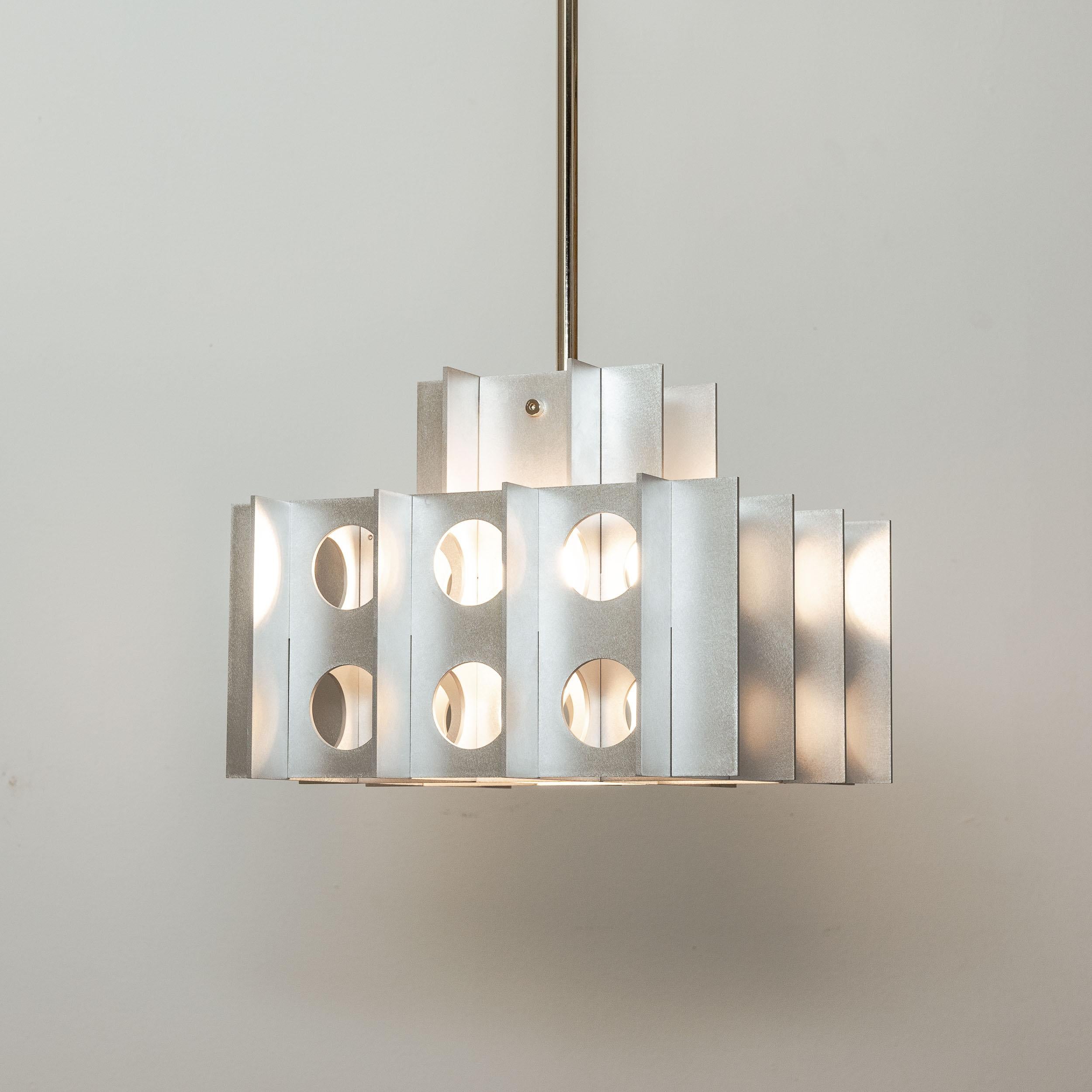 Tenfold Pendant 3TA in Waxed Aluminum by Luft Tanaka Studio

Composed of interlocking sheetmetal panels, the Tenfold Series is inspired by the aesthetics, architectural styles, and art movements of the 1970s. The light fixture works well as a single