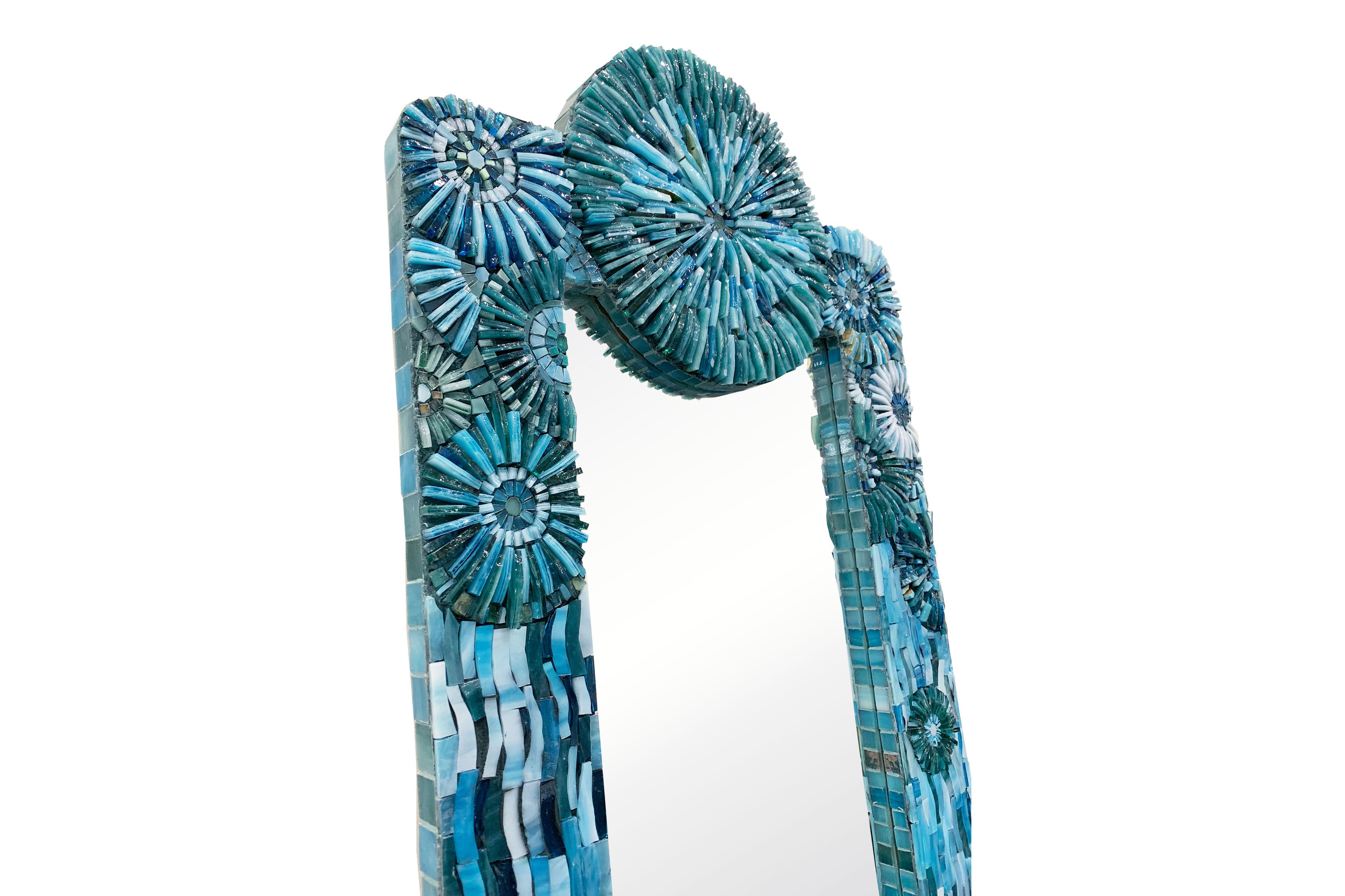 Le miroir rectangulaire blossom d'Ercole Home a une bordure de 3''.
Des mosaïques de verre taillées à la main dans différentes nuances de turquoise décorent la surface en motifs de fleurs et d'éclats.
Des tailles et des finitions personnalisées