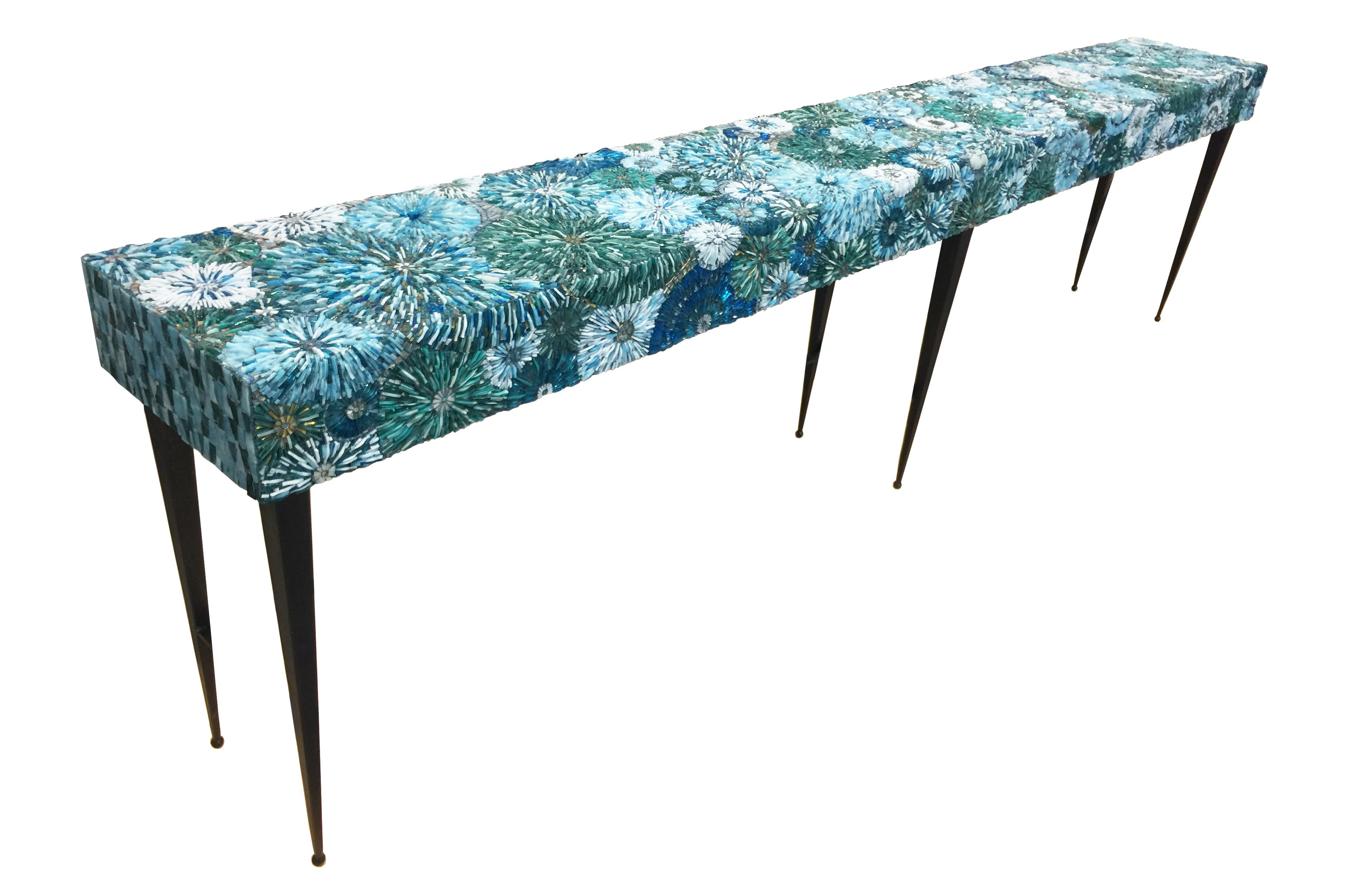 The pavia blossom console by Ercole Home has a 3-dimensional flower mosaic top with metal base.
Handcut glass mosaic in variety shades in Turquoise decorate the surface in Blossom pattern.
The metal base is in Natural Steel finish.
Custom sizes
