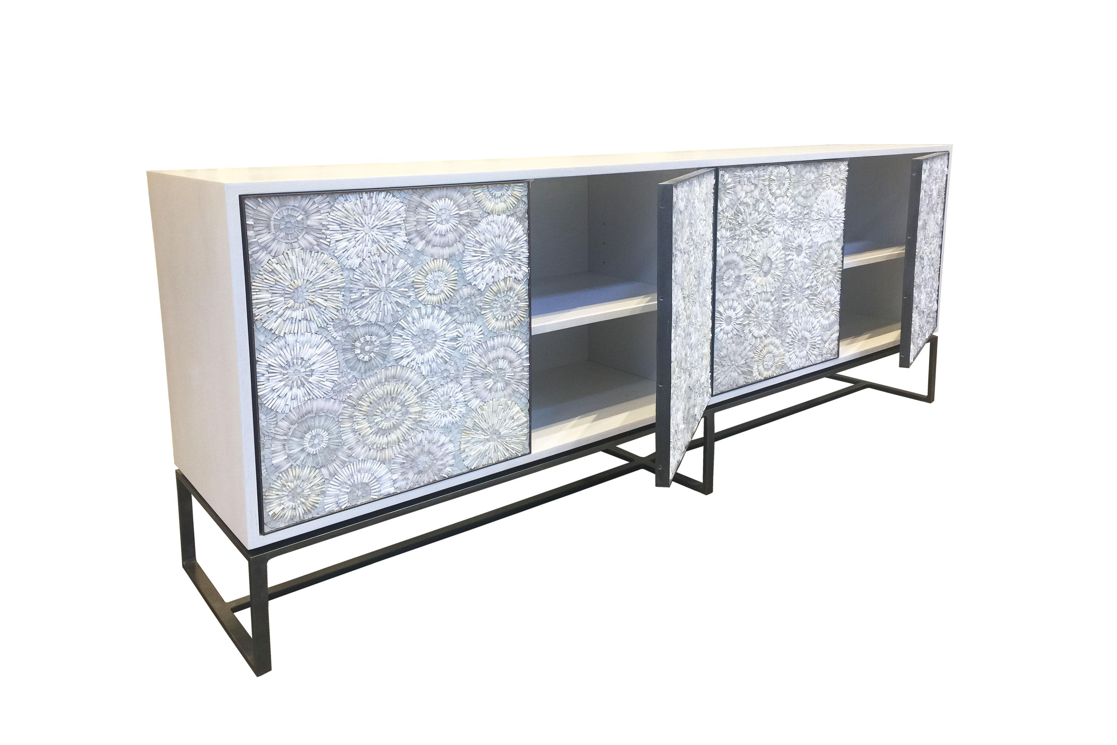 The Blossom serving buffet by Ercole Home has a 4-door front, with hand-hammered metal base and door frames in bronze finish. 
Handcut glass mosaic in variety shades of white and ivory decorate the surface in Blossom mosaic pattern.
Washed White
