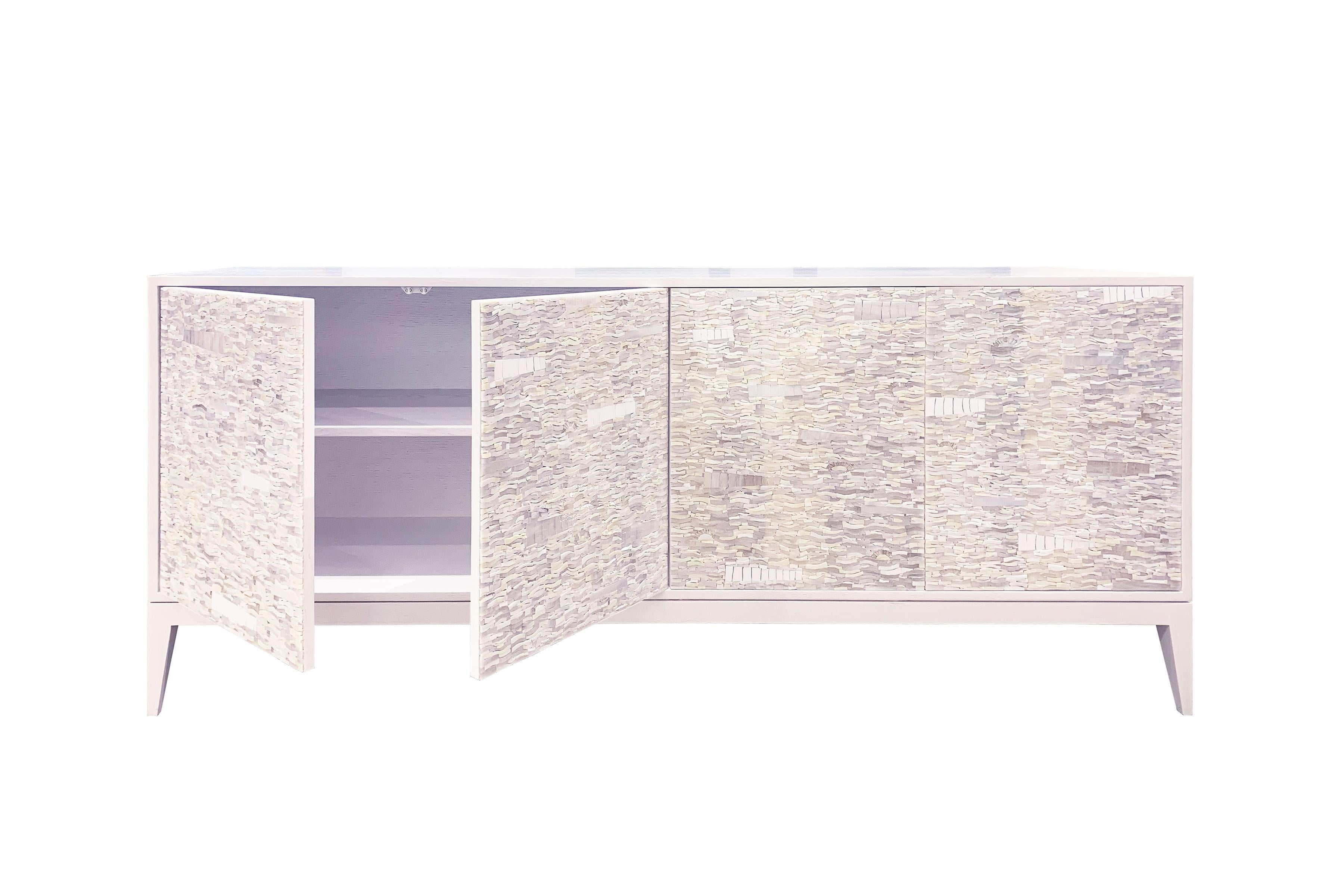 Der Schrank Ravenna von Ercole Home hat eine 4-türige Front und ist aus weiß lackiertem Eichenholz. 
Handgeschliffenes Glasmosaik in verschiedenen Weiß- und Elfenbeintönen verziert die Oberfläche im Ravenna-Mosaikmuster.
Jedes Fach verfügt über